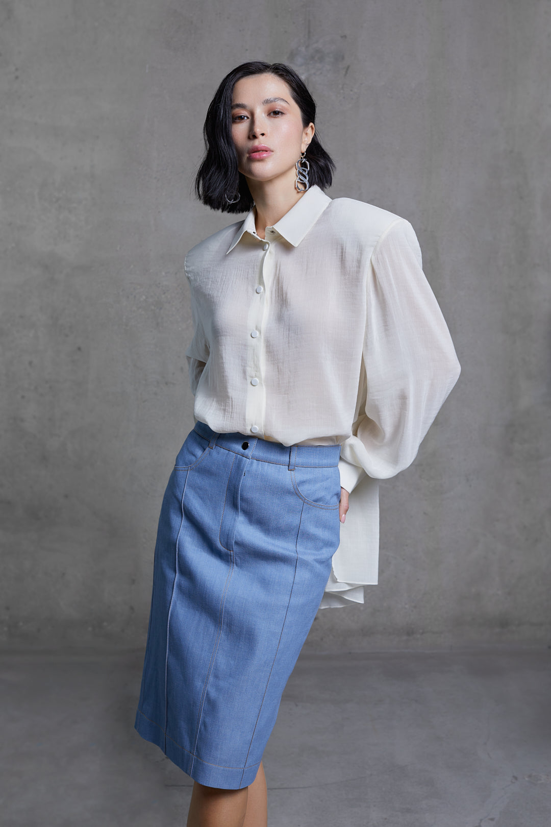 Three-quarter view of sheer white blouse with pointed collar and padded shoulders