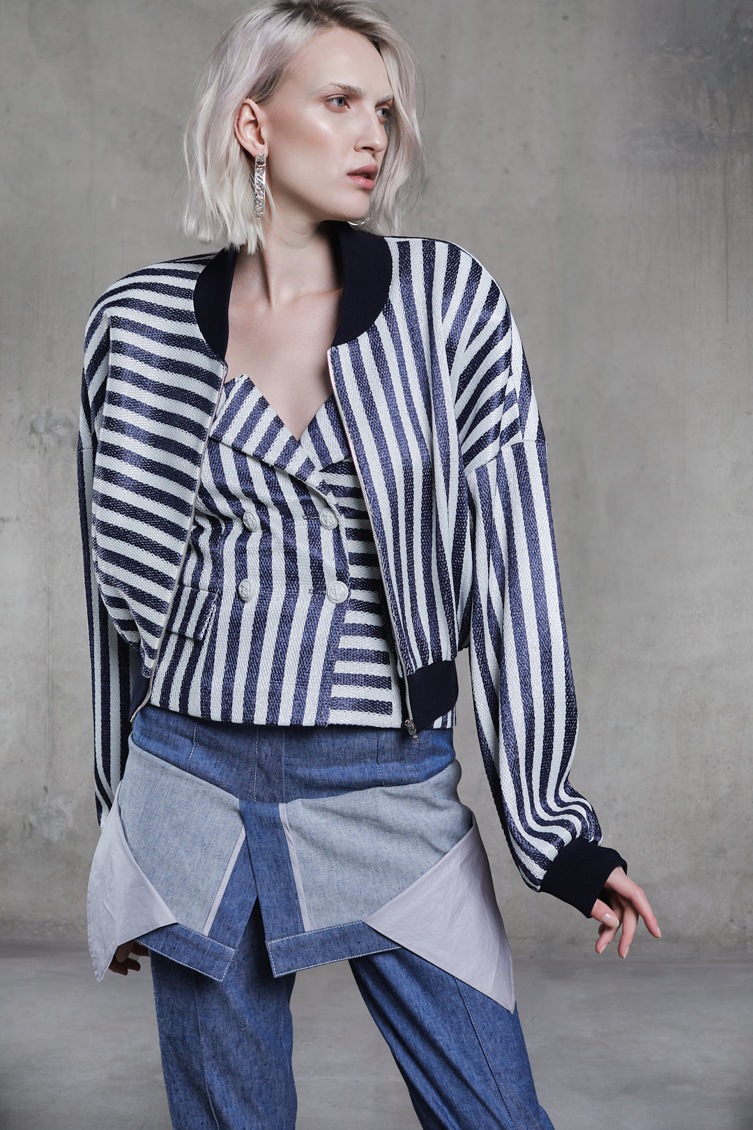 Double Breasted Stripped Raffia Corset layered with matching striped bomber jacket and blue panel trousers, three-quarter studio view