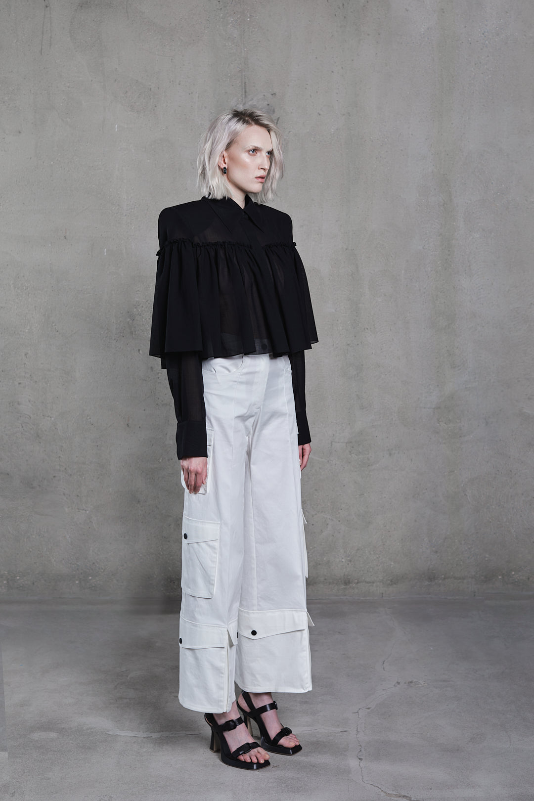 SAGIO black cotton blouse with ruffle front and structured shoulders and White silk cargo trousers with multiple pockets and wide fit