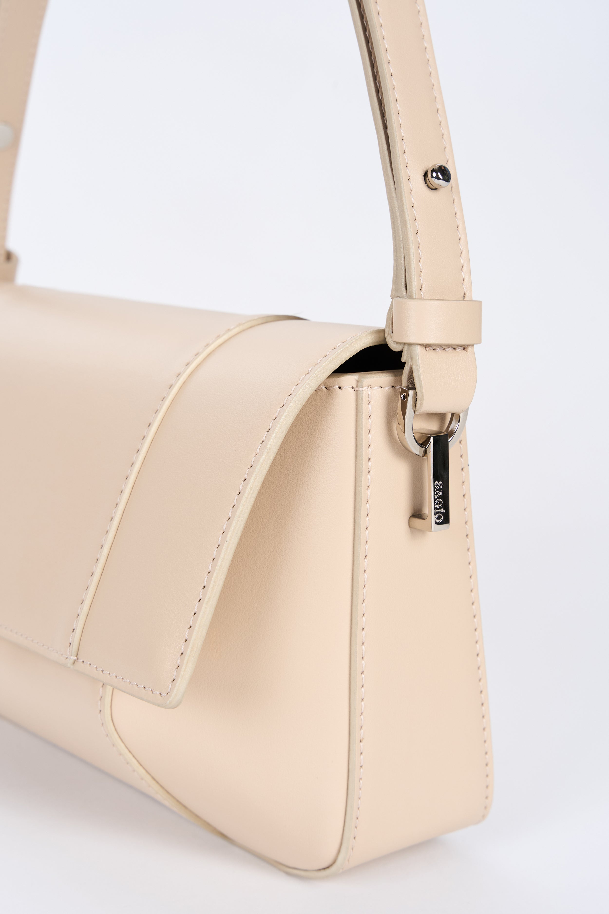 Beige smooth lambskin bag side detail with curved flap and strap hardware