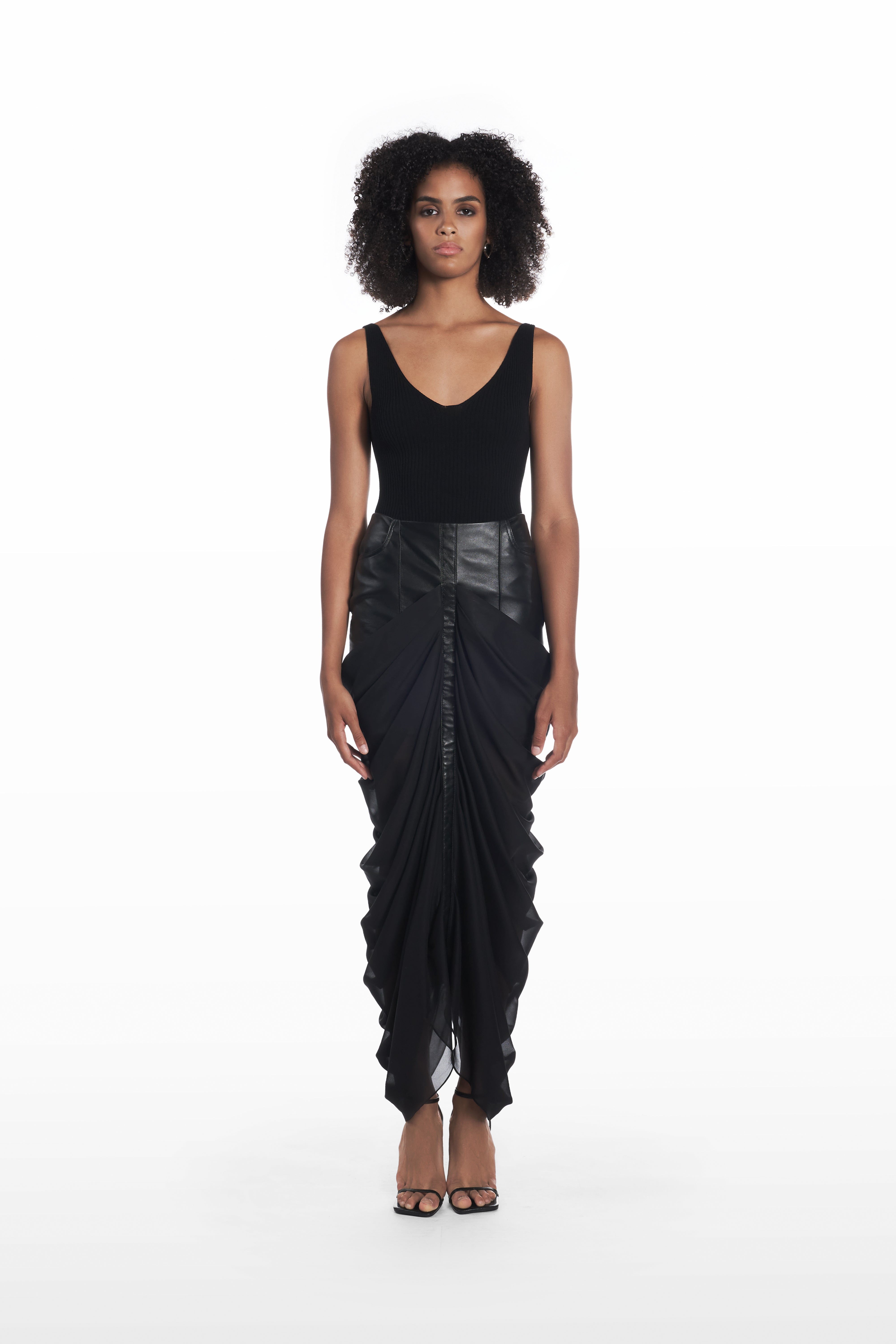 Black draped leather skirt full front view on model with fitted black top