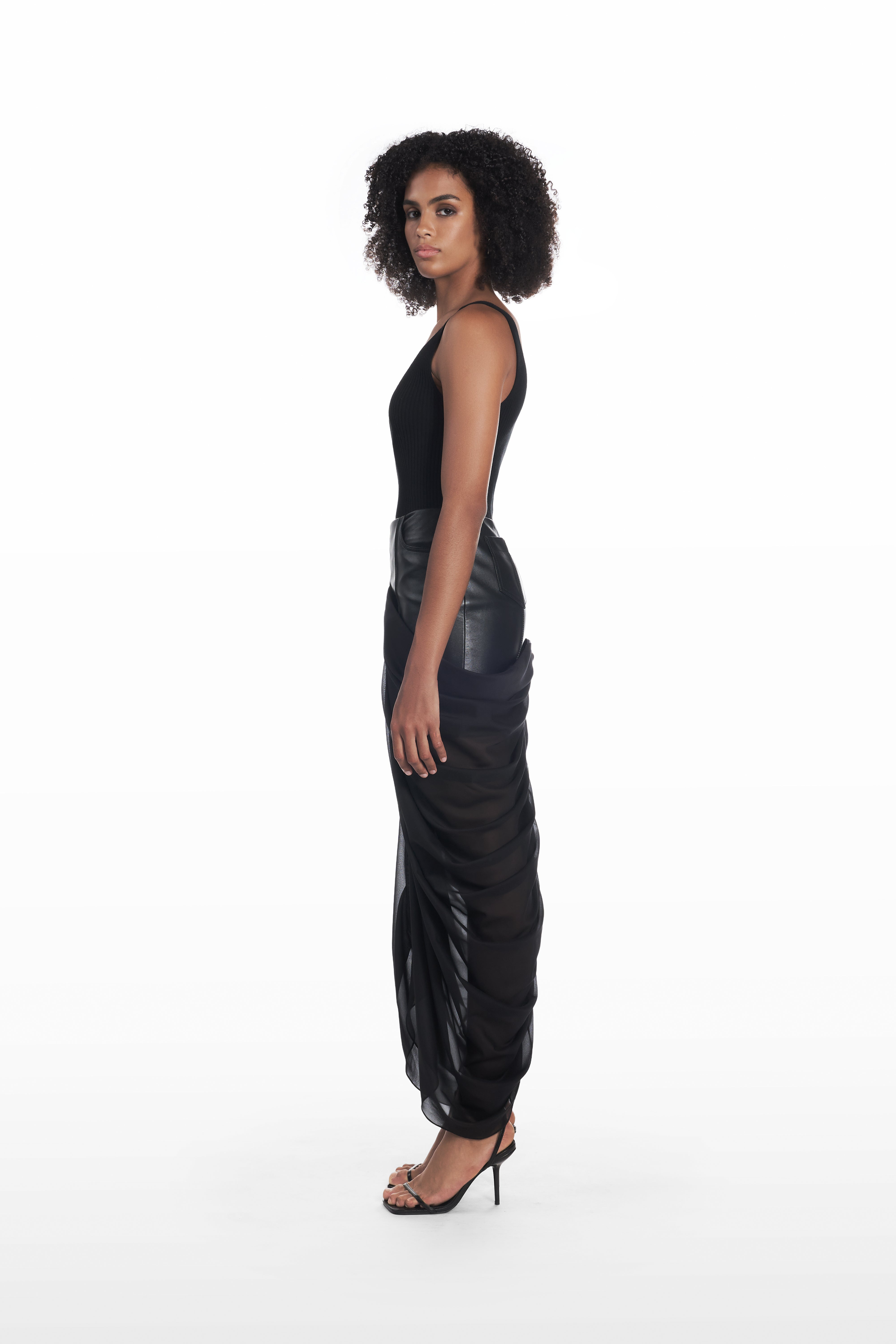 Black sculptural draped skirt side view on model with sheer layered silhouette