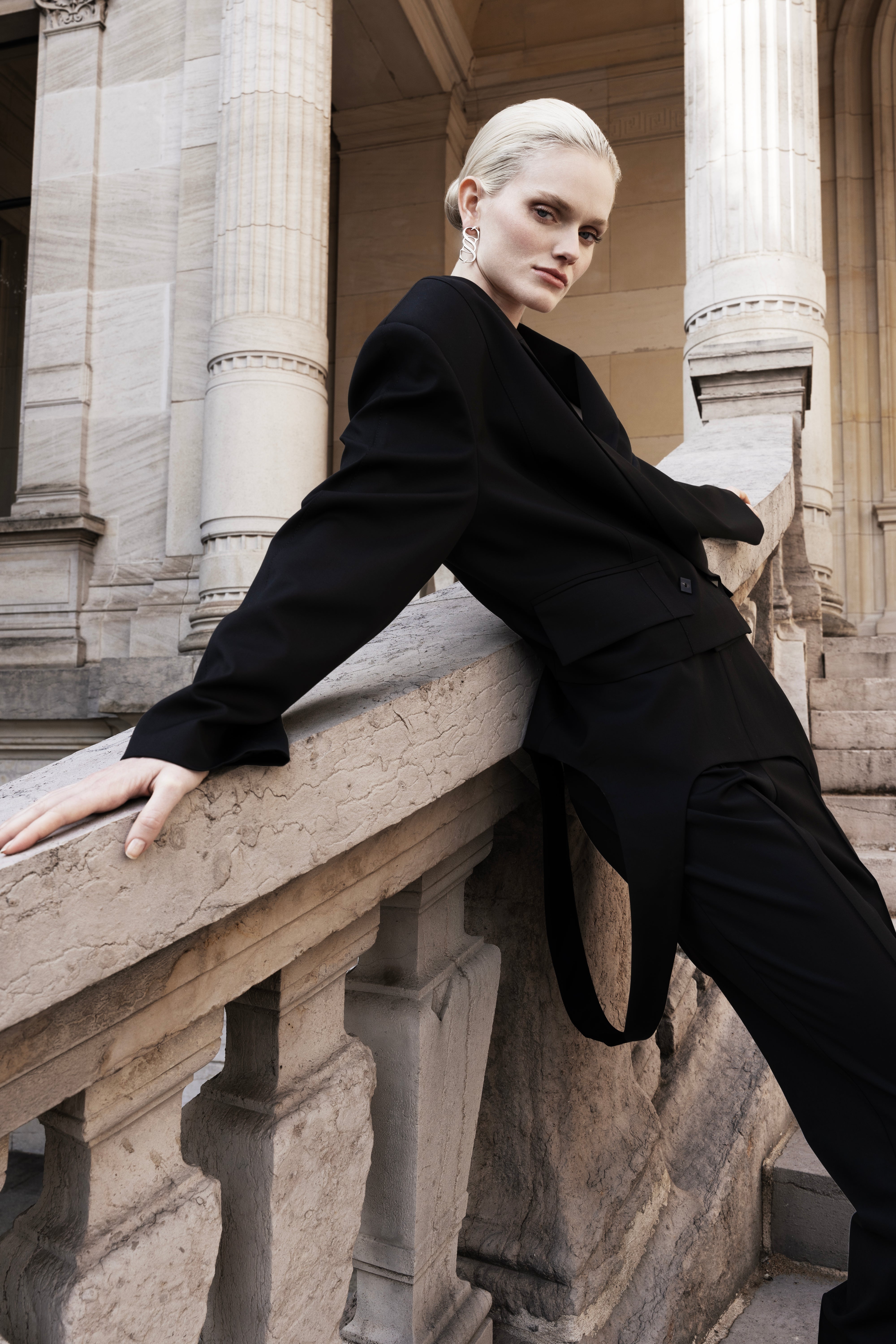 Women’s black wool tailored trousers with draped panel, styled with a black blazer