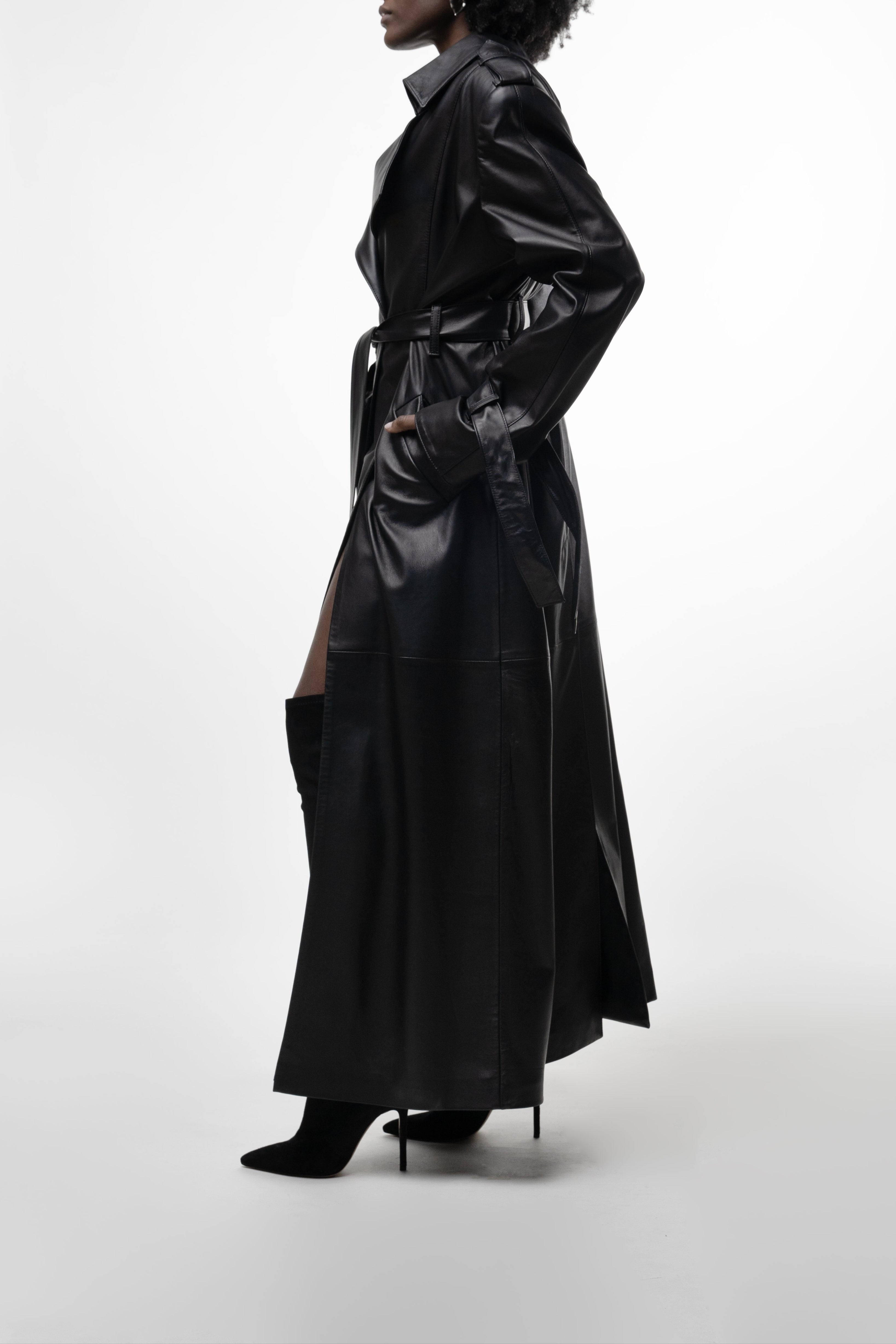 Model in long black leather trench with belt and high side slit