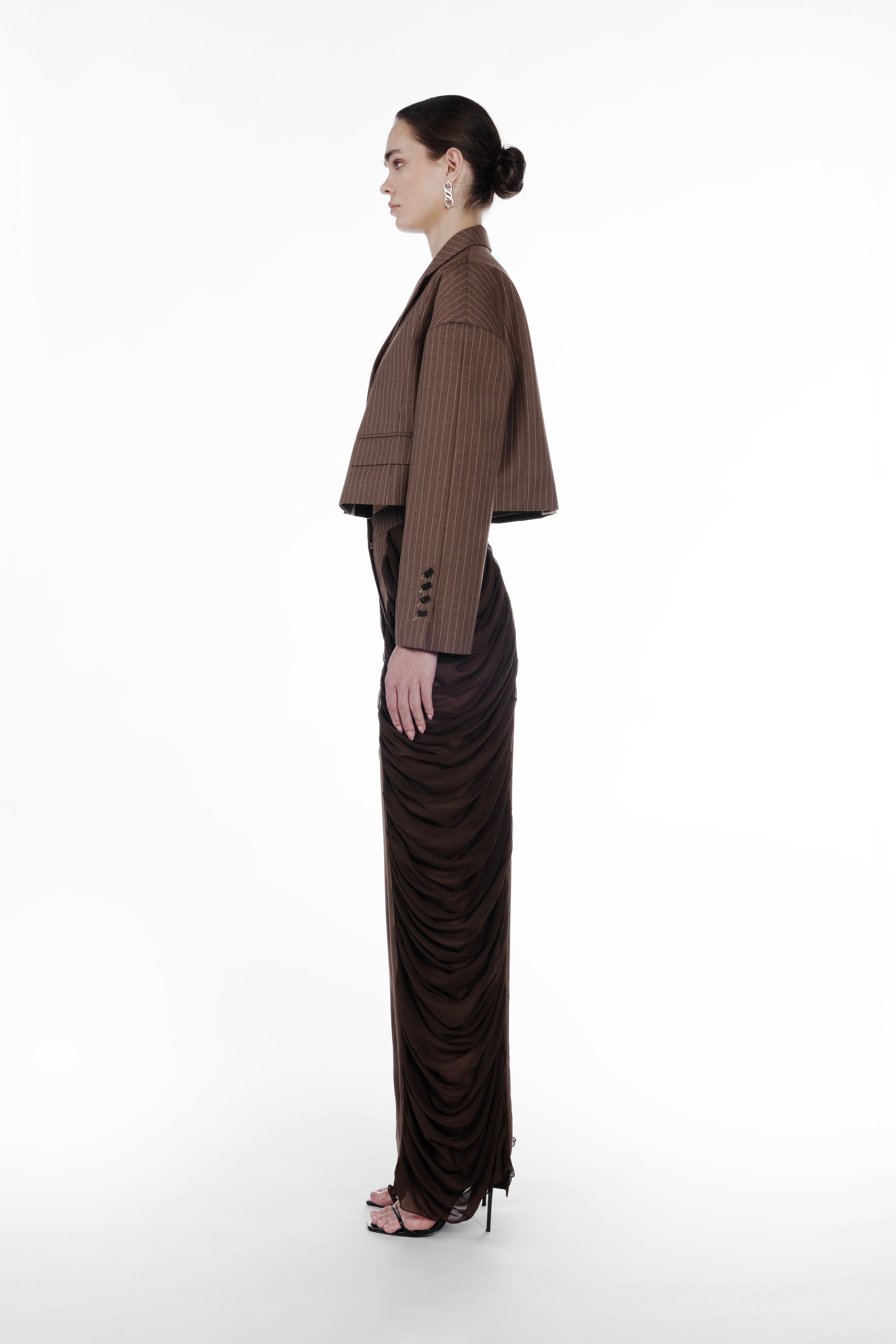 Silk Folds Stripes Trousers in Brown, side view, luxury pinstriped trousers with draped silk side panels, elongated straight leg and tailored high-rise fit. Falling Shoulders Stripes Jacket by SAGIO in brown beige pinstripe wool, side view, cropped silhouette with dropped shoulders and fluid draped detailing