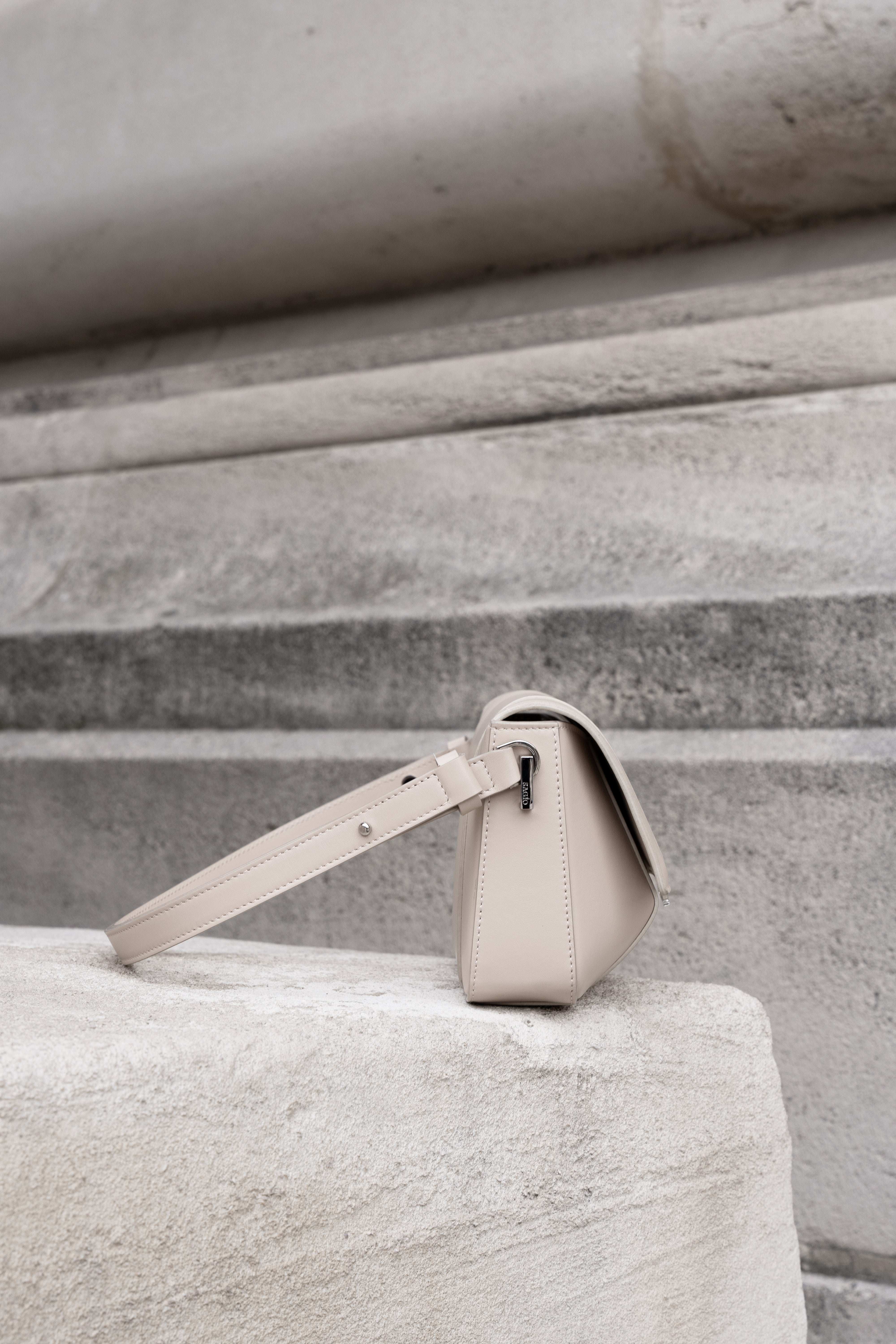 Beige Il Cupola leather bag side view styled on stone surface