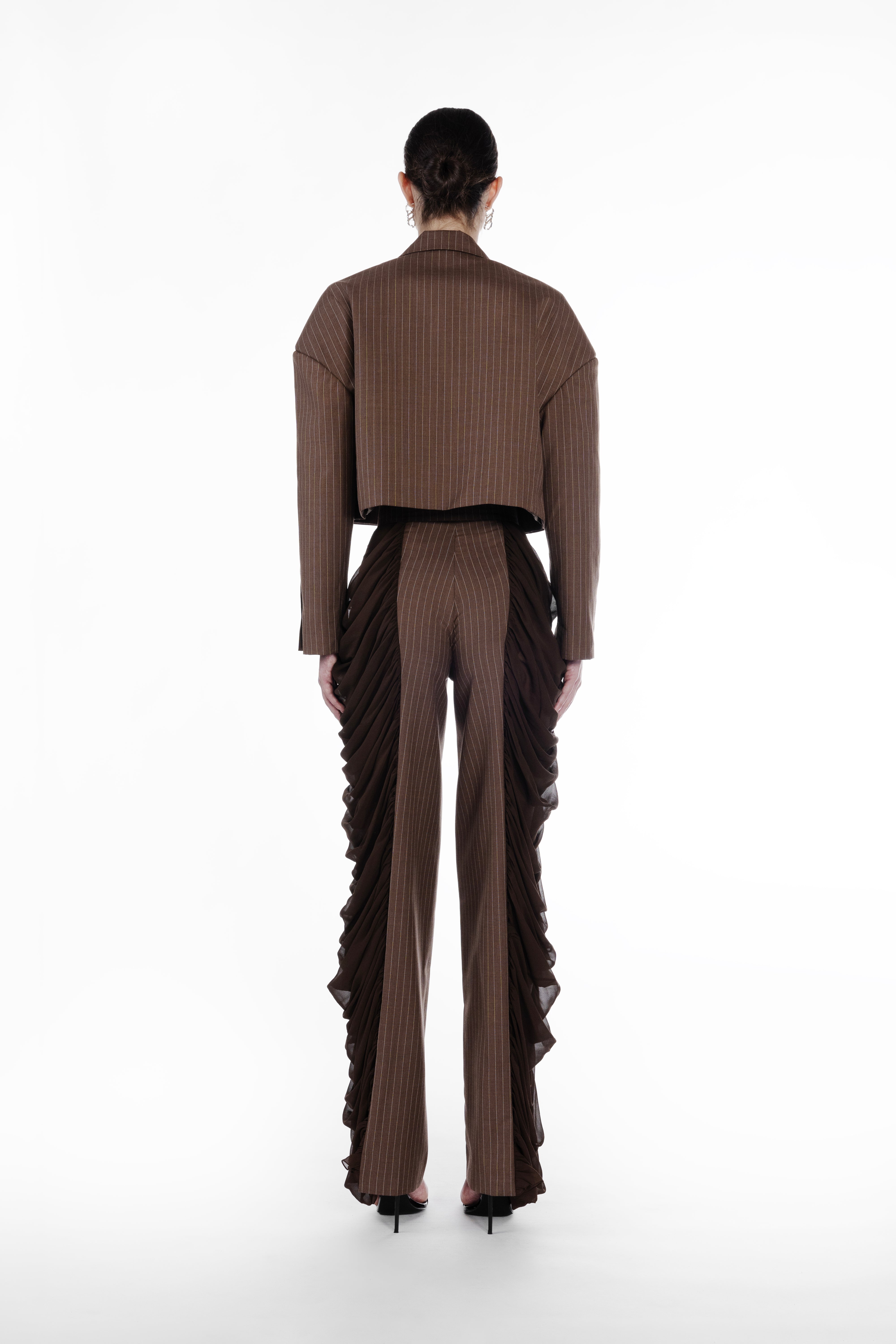 Silk Folds Stripes Trousers in Brown, back view, tailored striped trousers with flowing silk folds along the sides and a clean elongated silhouette. Falling Shoulders Stripes Jacket by SAGIO in brown beige pinstripe wool, back view, structured cropped jacket with sheer gathered side panels