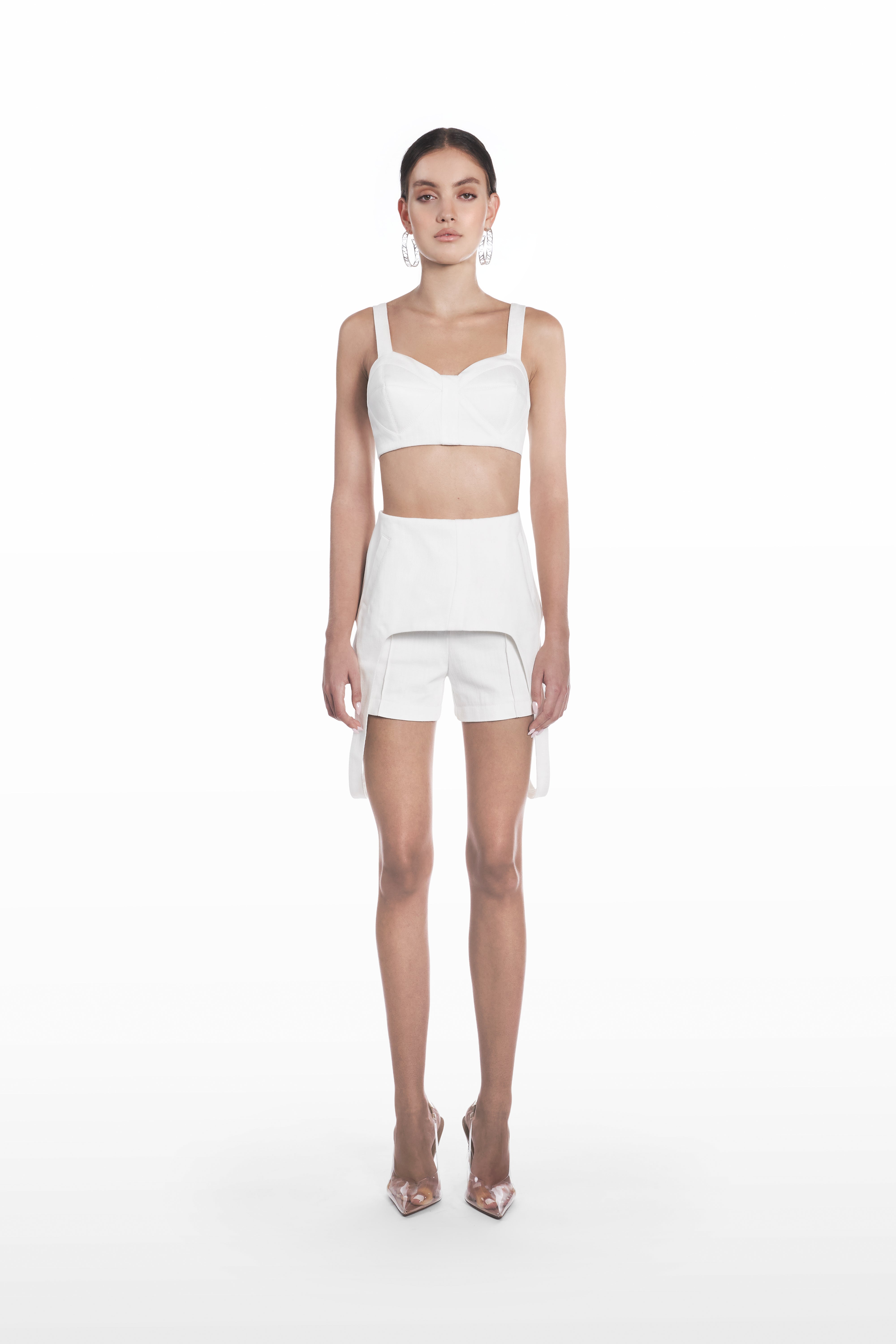 Denim falling shorts in white, front view with sculptural overlay and tailored silhouette styled with a matching cropped top