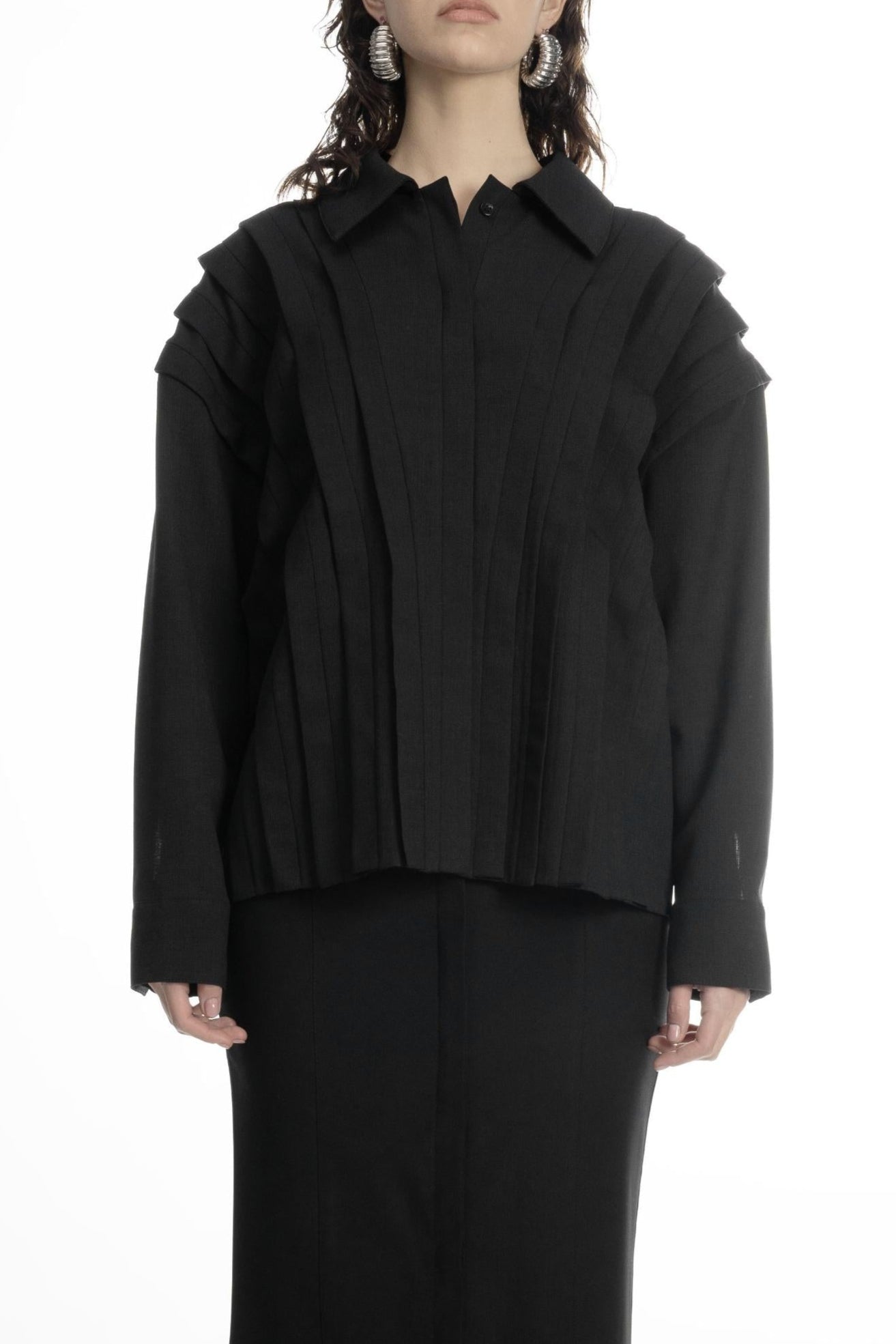 Woman wearing black wool pleated-placket blouse with collar and long sleeves, styled with long black skirt