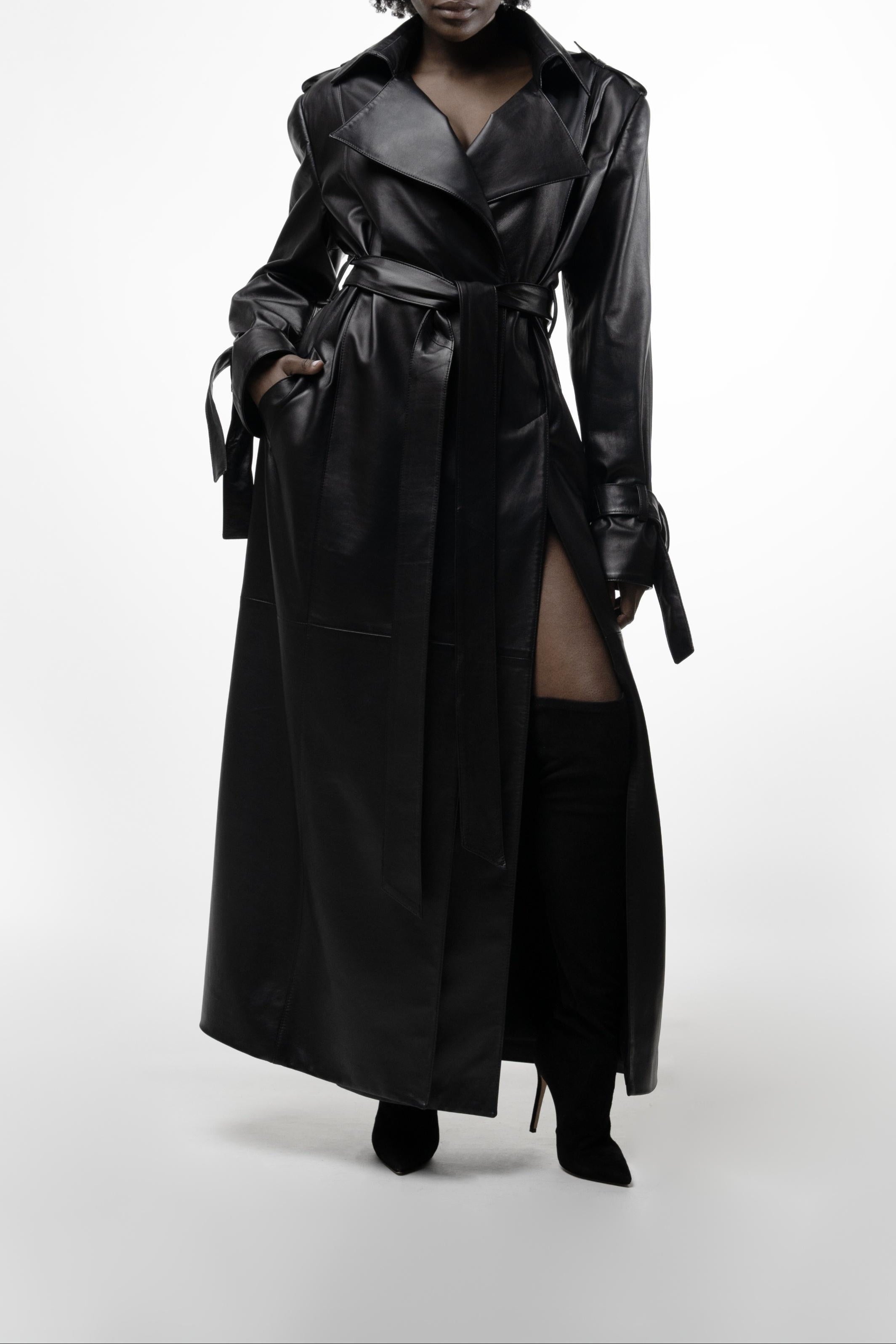 Model wearing long black leather trench with dramatic thigh-high slits