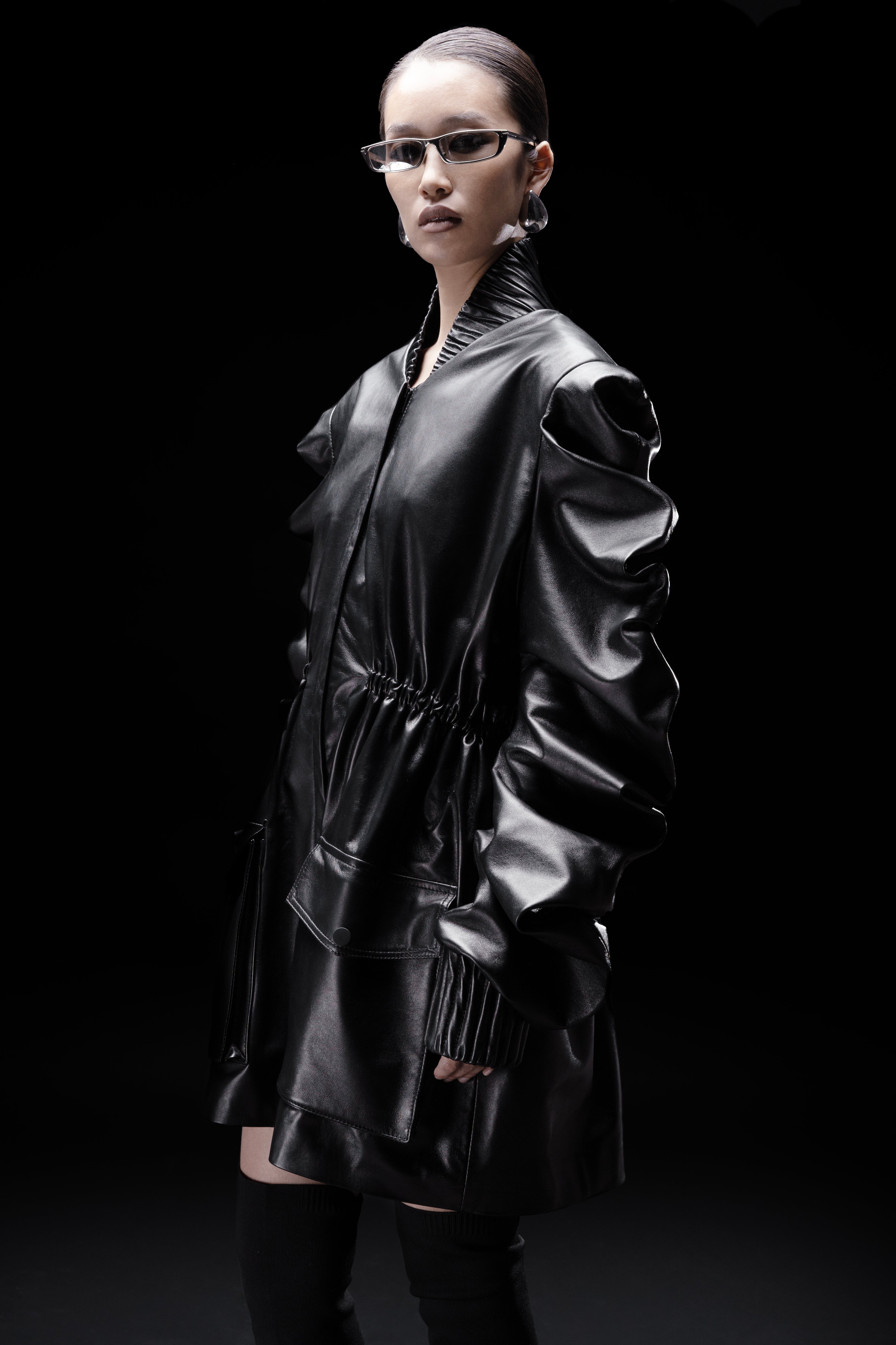 Woman in designer black Leather Medusa Parka with sculptural sleeves