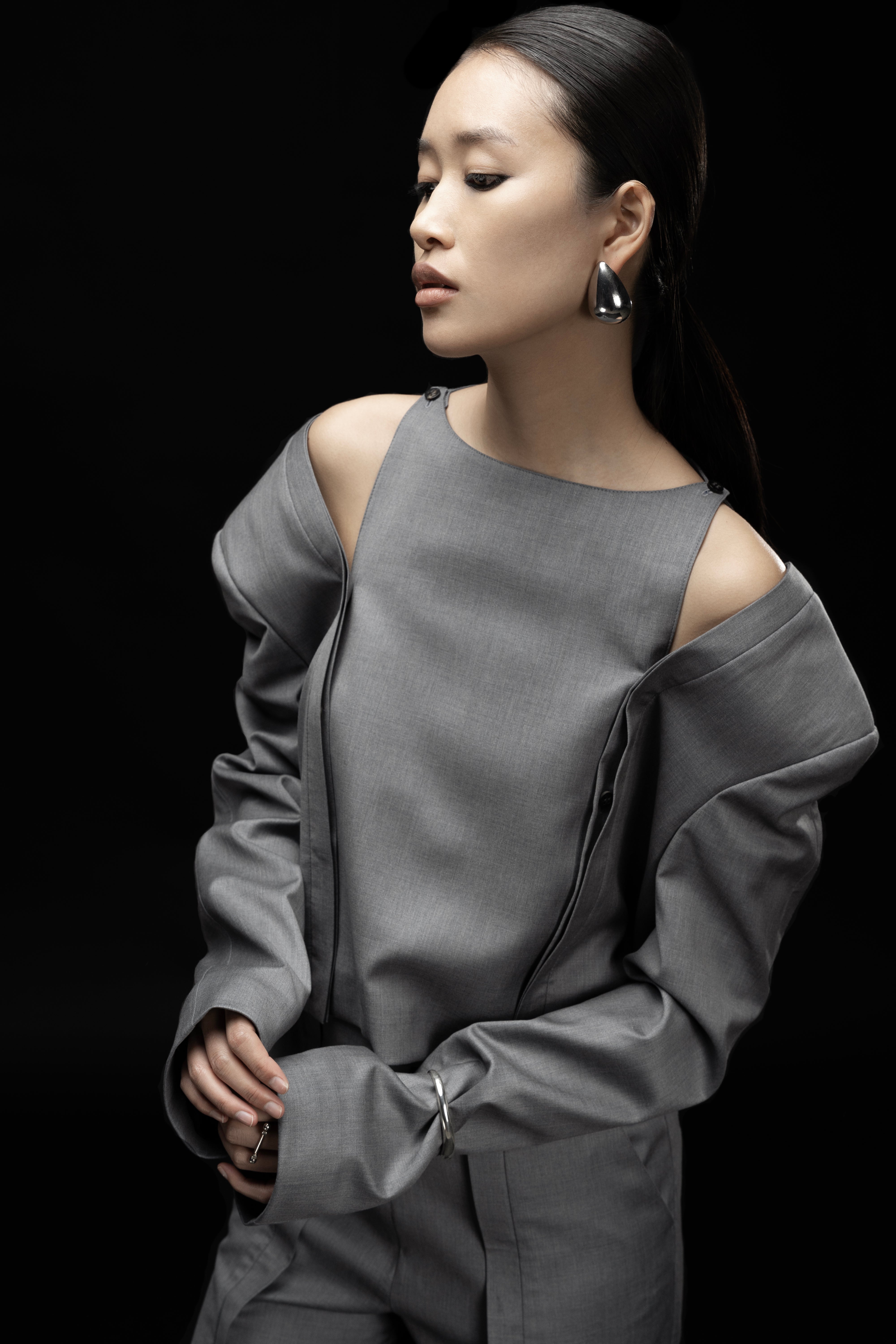 Close-up of Open Shoulder Short Jacket in light grey, 100% wool with viscose lining, showing the signature open-shoulder construction