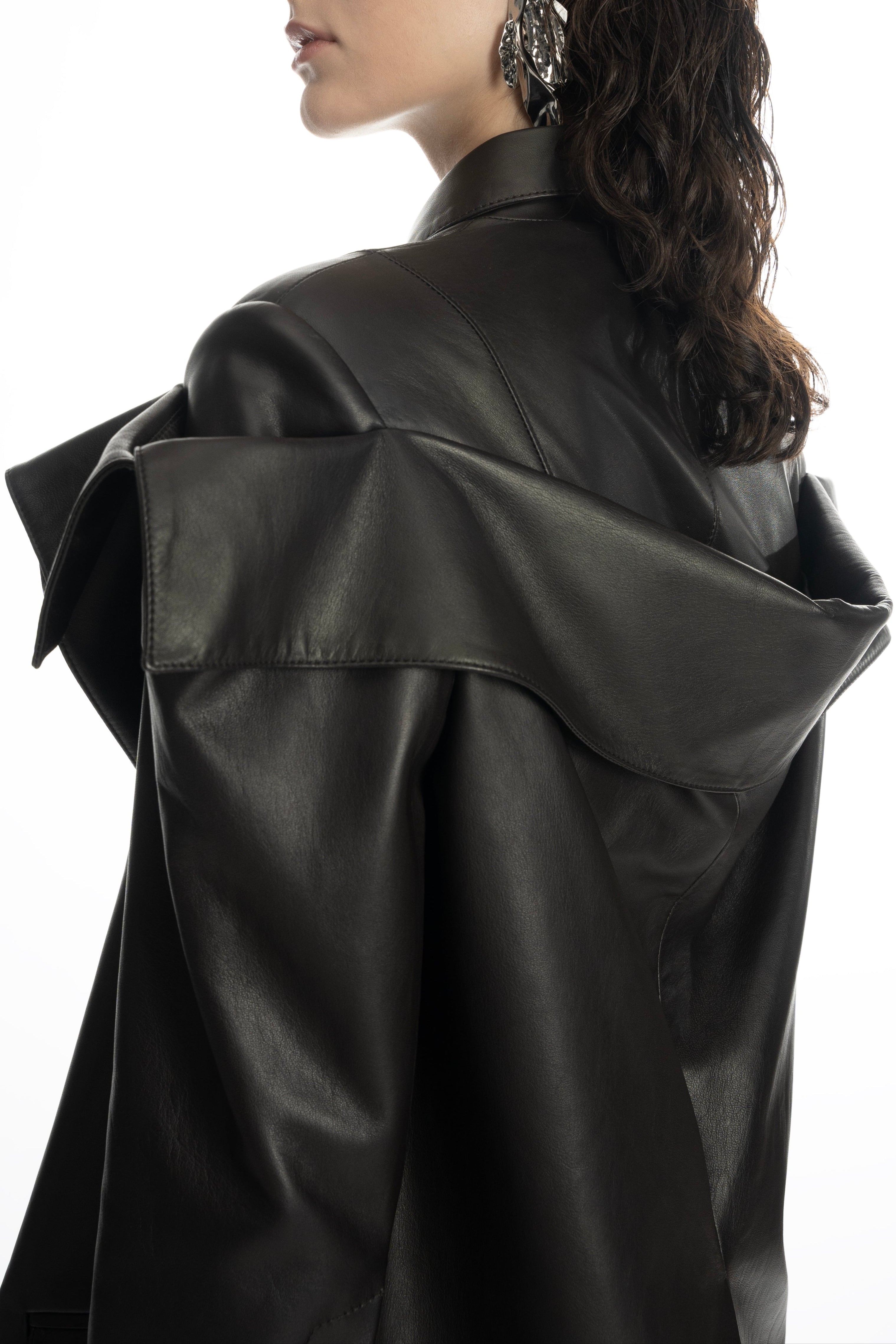 Close-up of the draped leather shoulder detail and smooth seams on the black jacket.