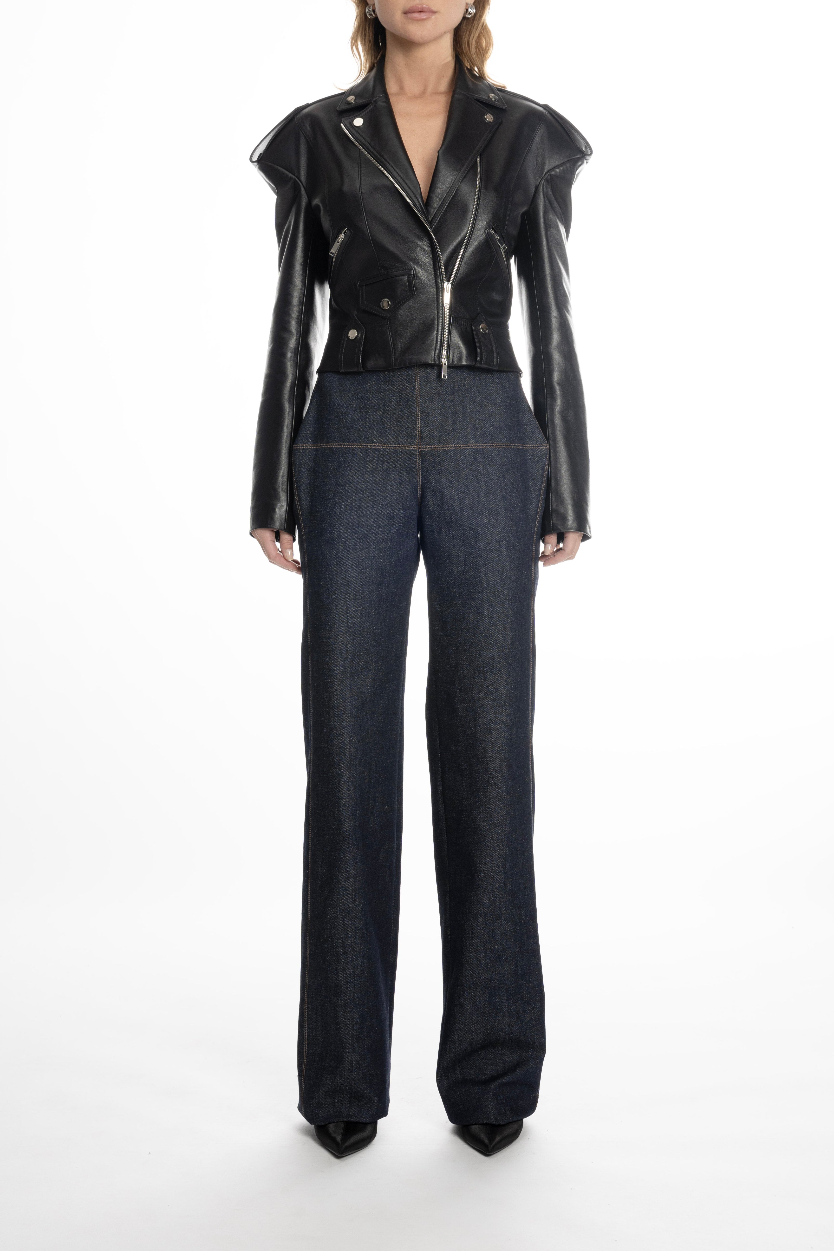 Model wearing black cropped leather biker jacket with jeans, highlighting sculpted falling shoulders and sharp lapels.
