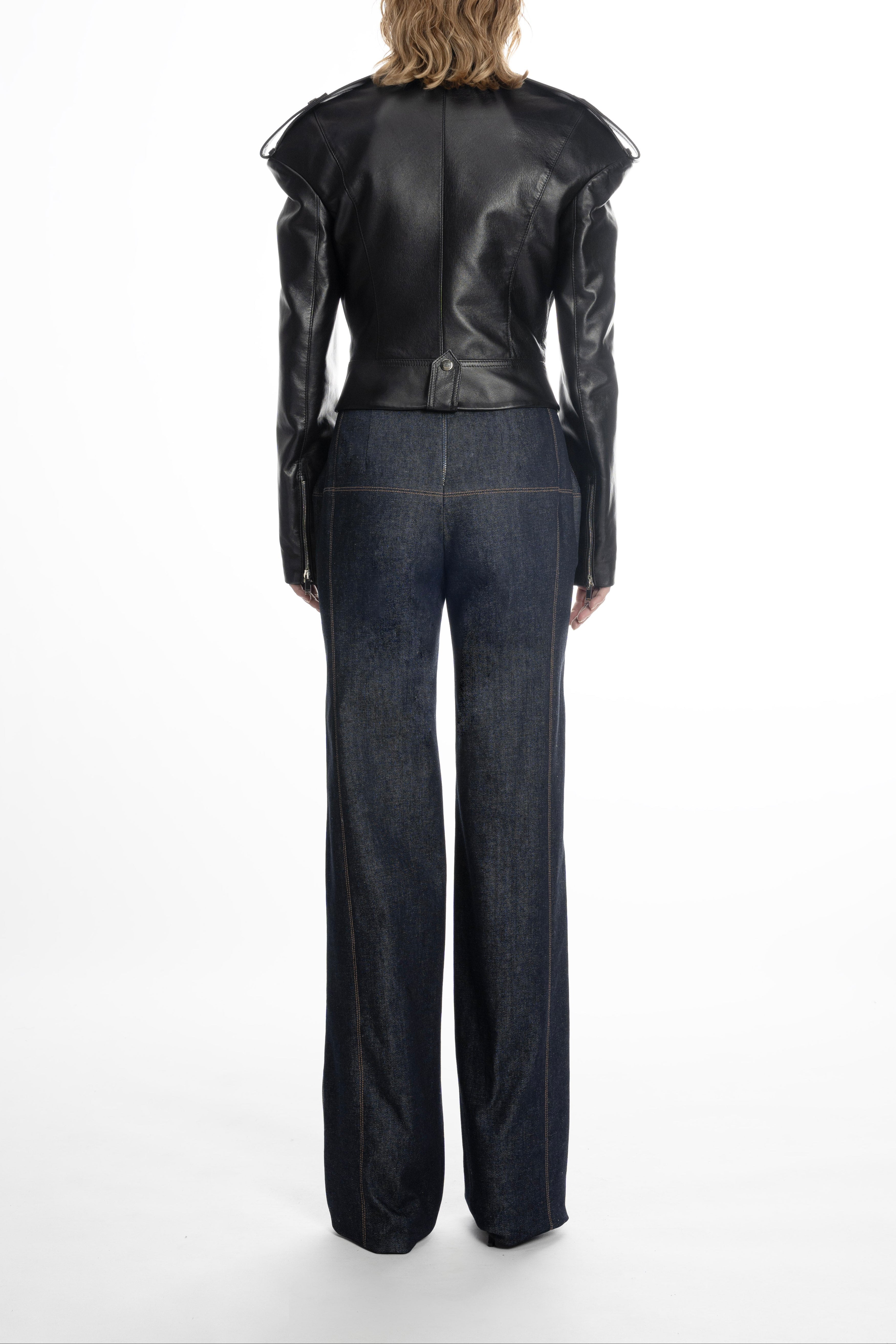 Model in cropped black leather jacket displaying structured back and cropped hem.