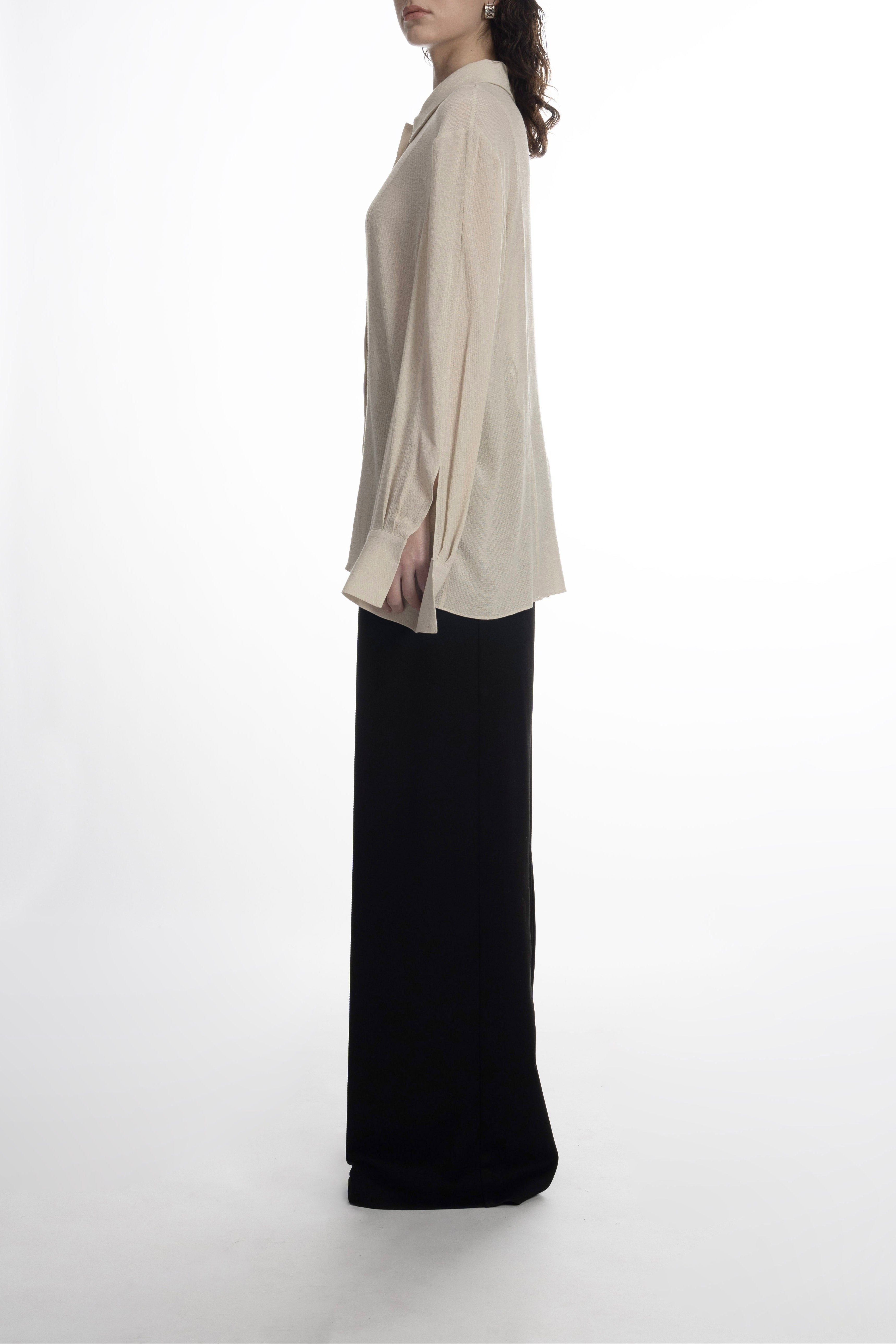 Relaxed-fit ivory blouse highlighting fluid fabric and extended cuffs.