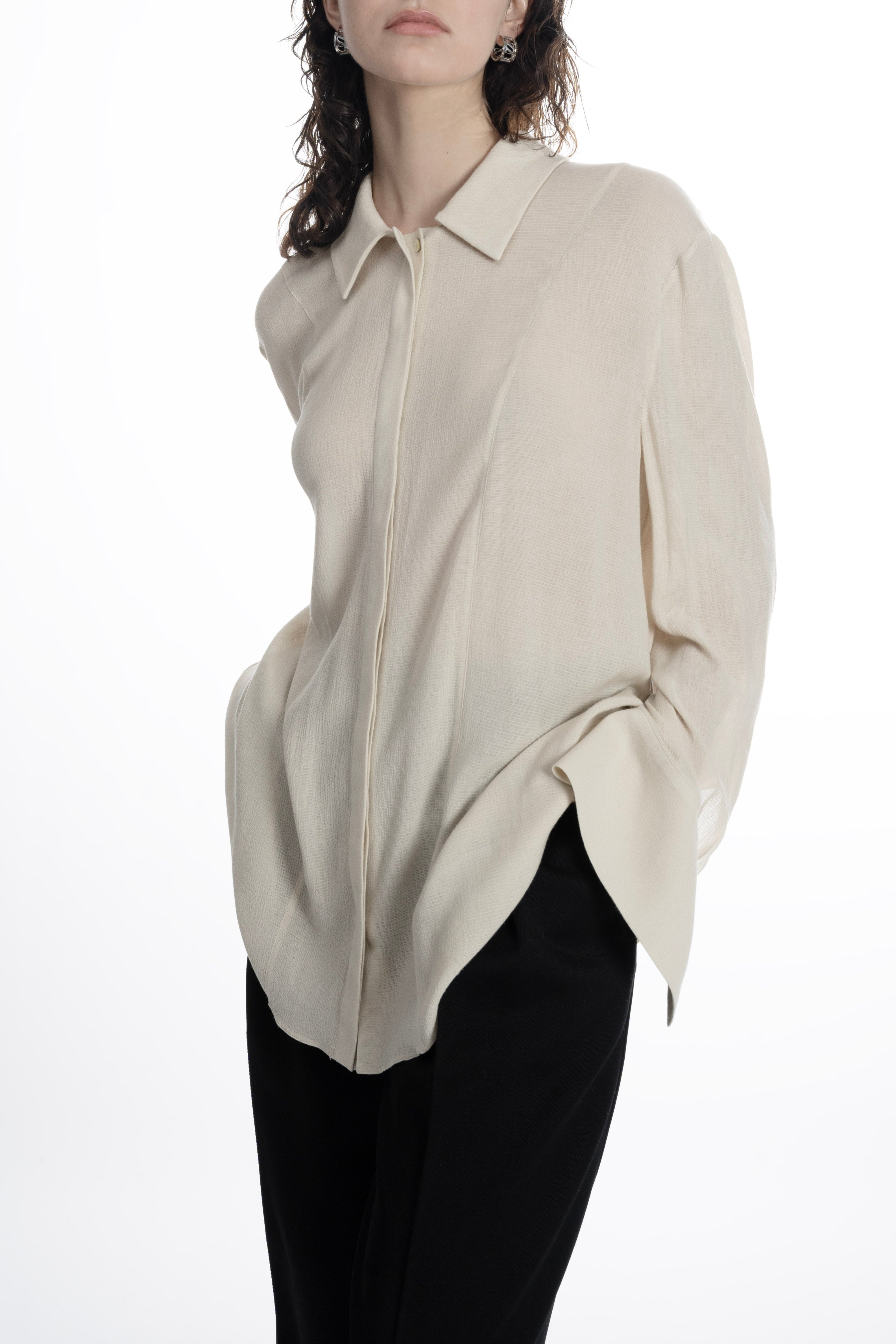 Close-up of collared ivory classic blouse with concealed placket and soft textured fabric.