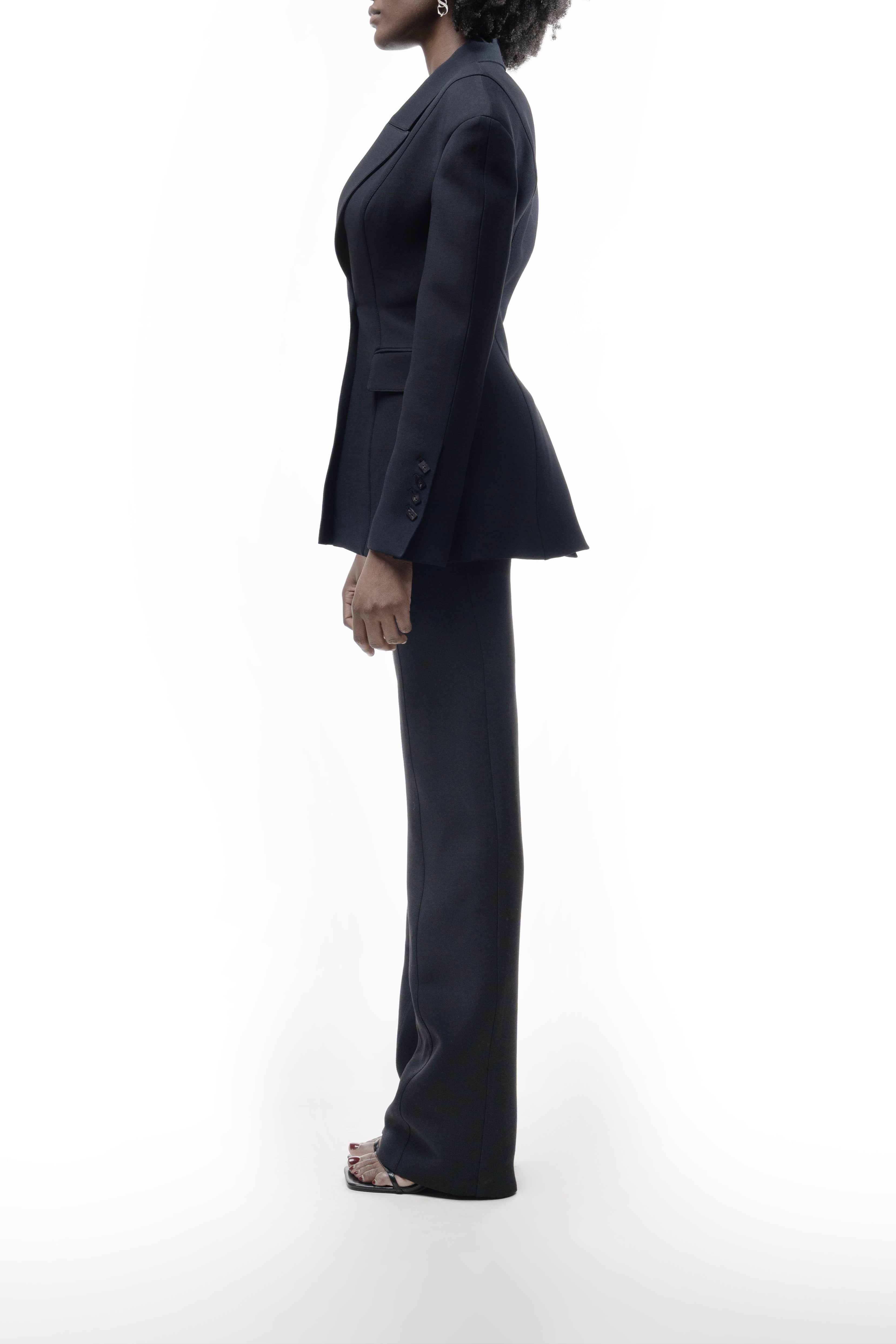 Black wool Falling Shoulders Jacket on woman, softened shoulder construction, sculpted waist and slight peplum over matching trousers