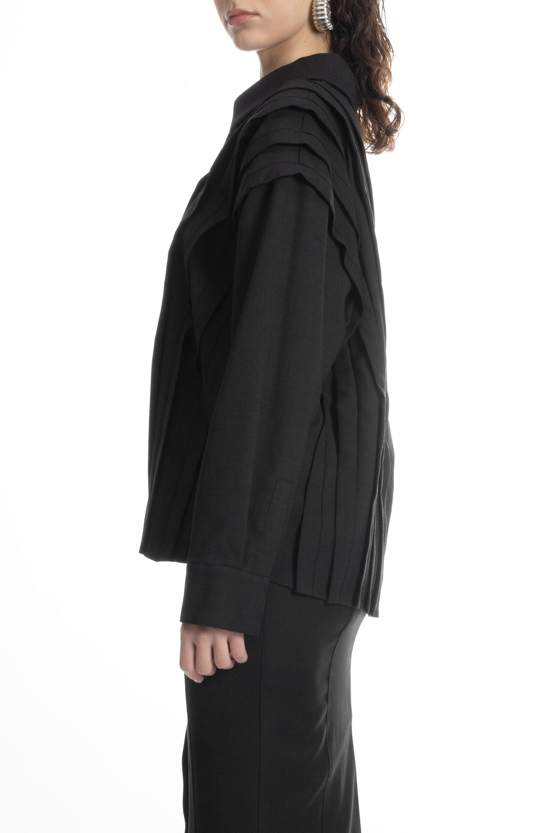 Black wool blouse featuring sculptural layered placket, collared neck and long sleeves, paired with long skirt.