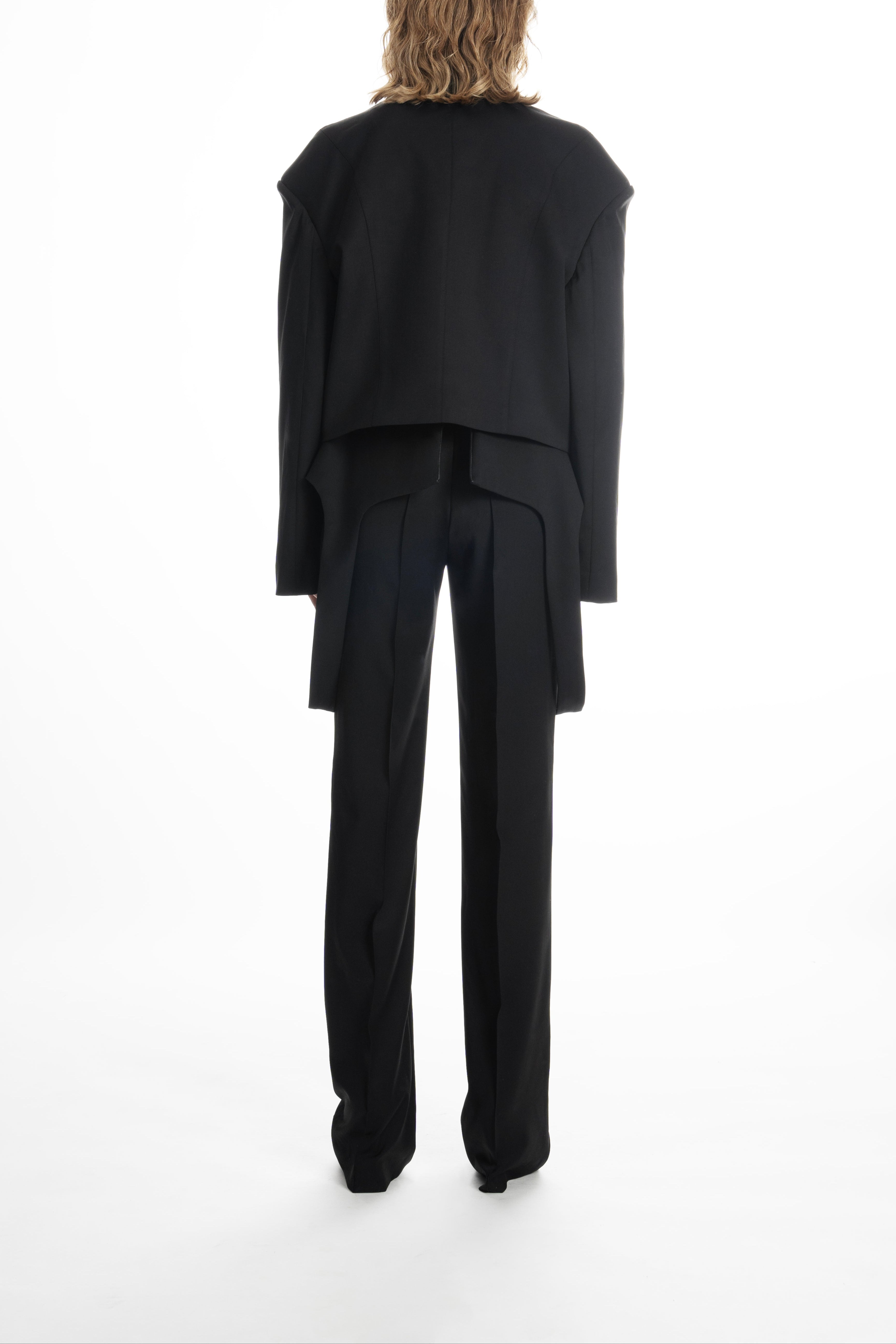 Woman in black cropped wool blazer, displaying tailored seams and cropped length.