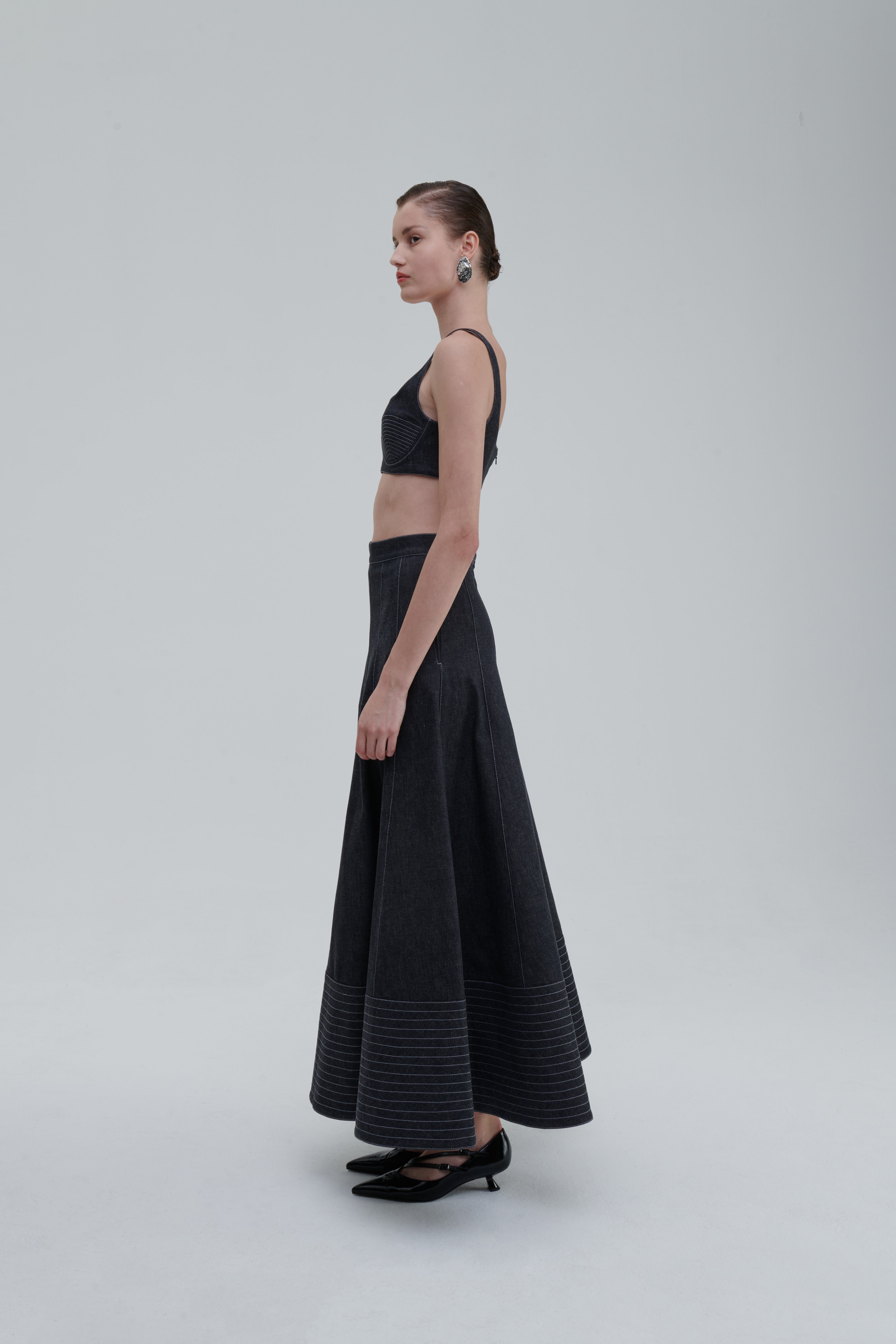 Anthracite quilted denim skirt on model, side view, contrast seam panels