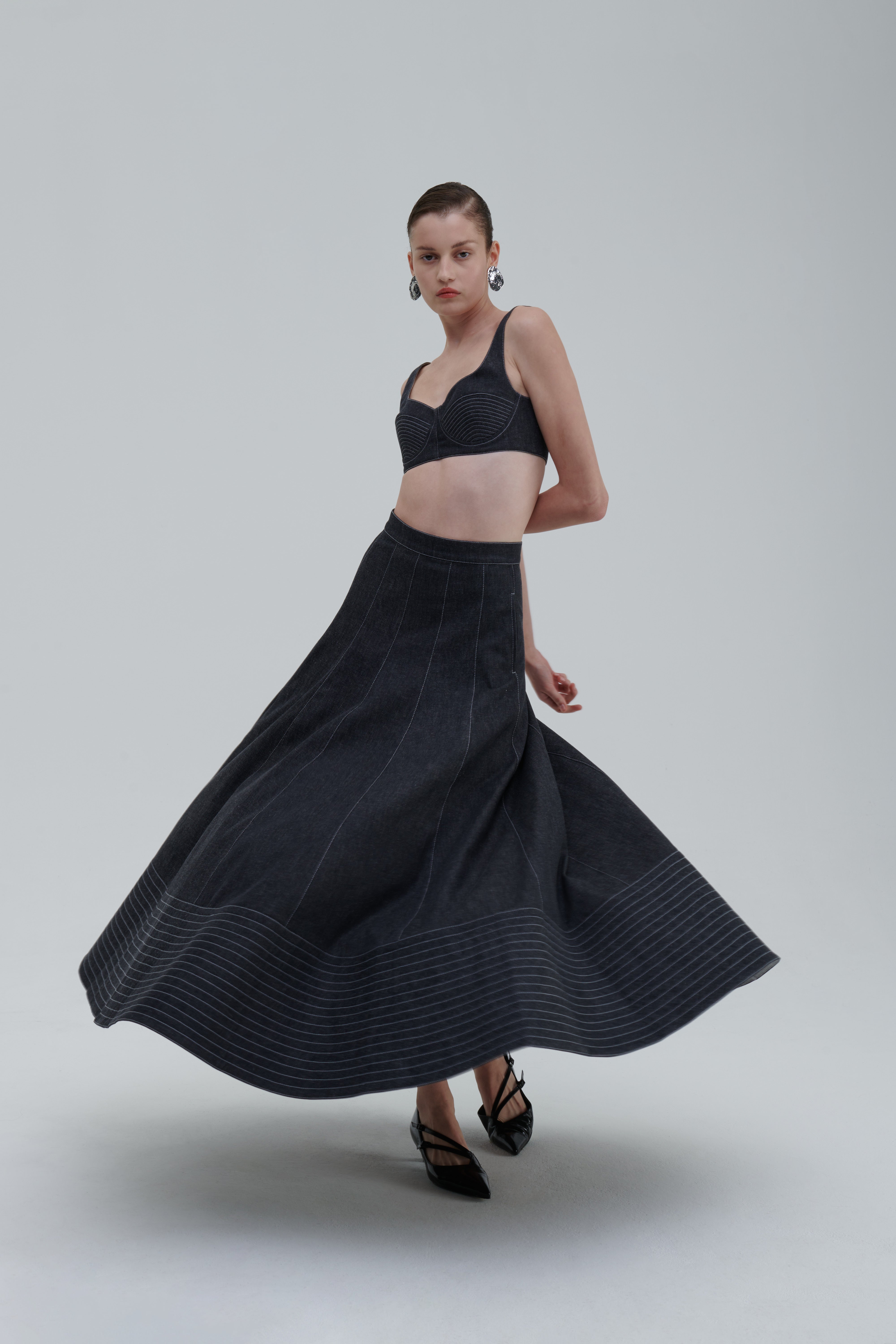 Anthracite quilted denim skirt, movement shot, flared hem detail