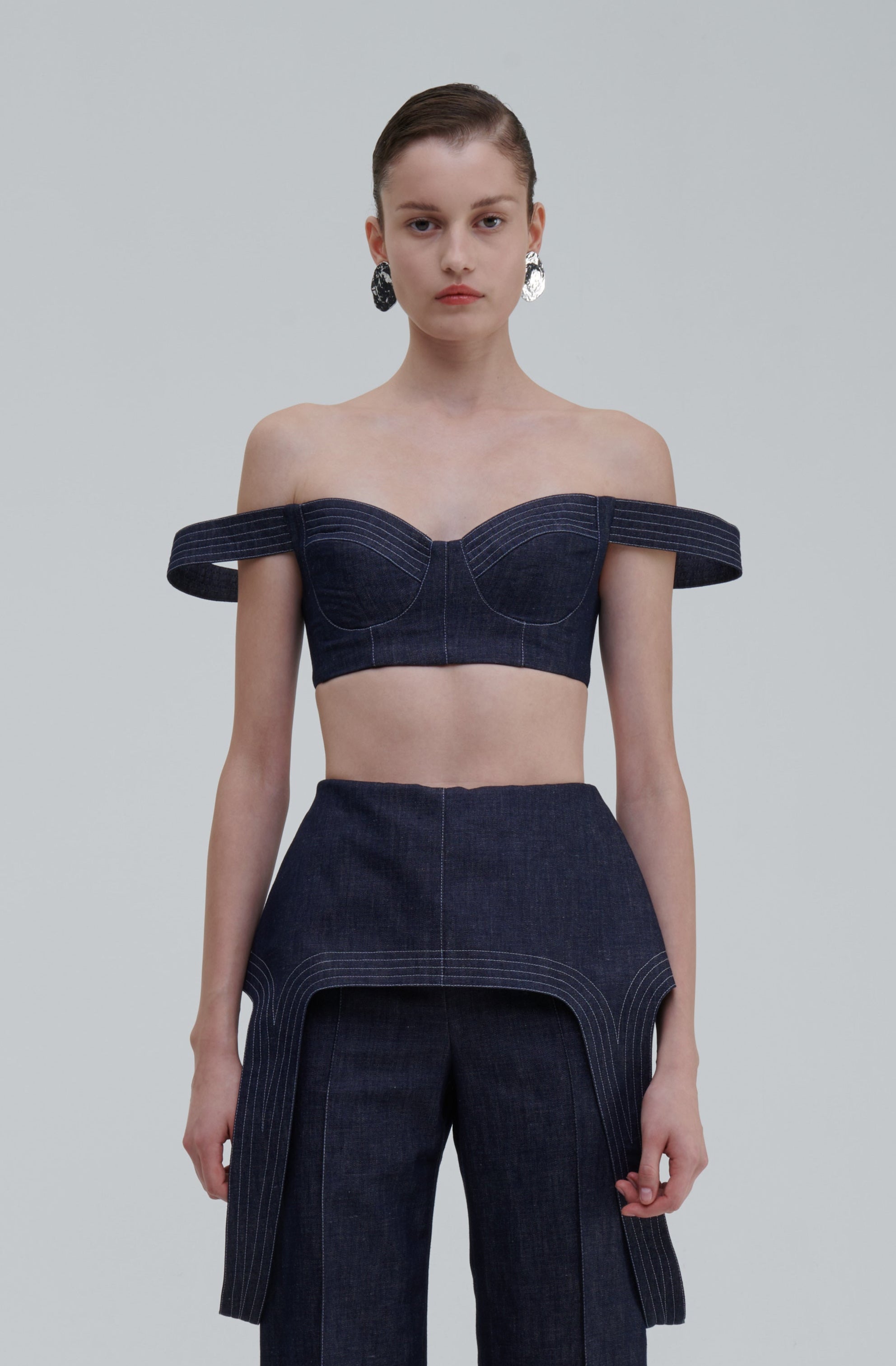 DENIM FALLING TOP by Sagio from the Spring/Summer 2025 collection, featuring a sculptural sleeveless denim top with an asymmetrical draped hem and minimalist neckline. Contemporary women's fashion available at thesagio.com
