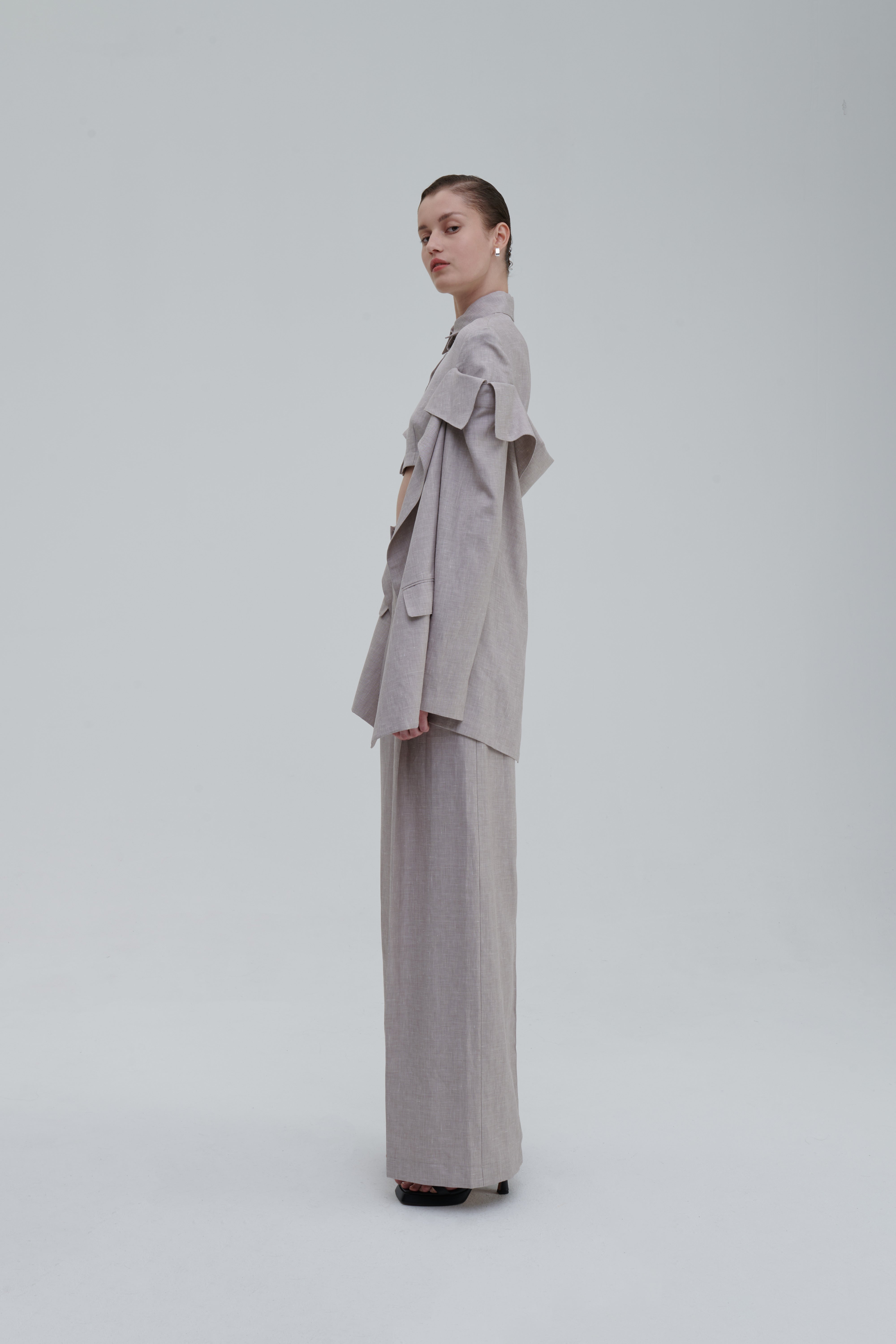 Fashion Classic Lino Trouserd by Sagio from the Spring/Summer 2025 collection, featuring wide-leg high-waisted linen pants in light beige, styled with a matching cropped top and statement sleeves. Discover more at thesagio.com.