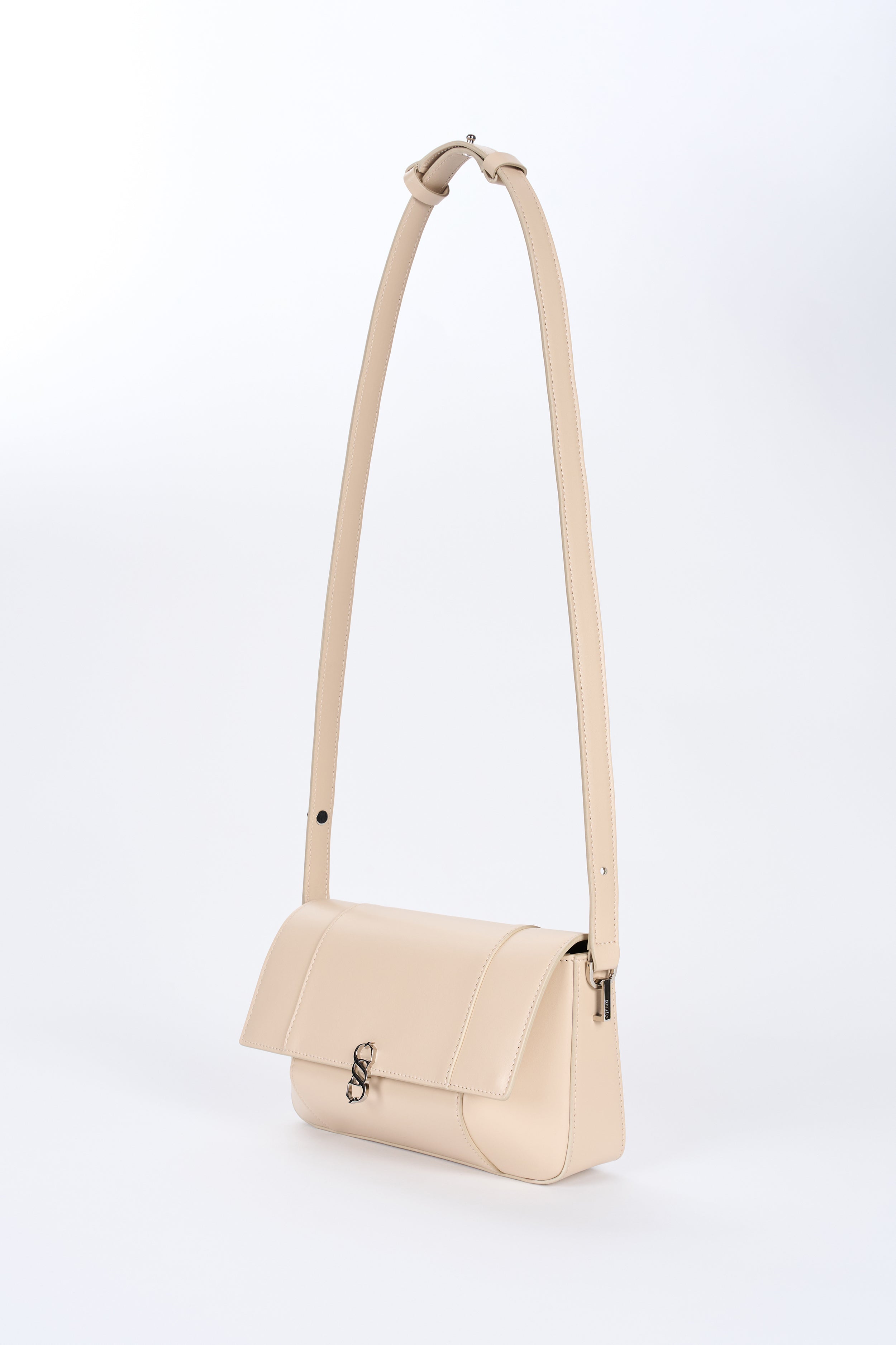 Beige Il Cupola bag angled front view with elongated strap and curved flap