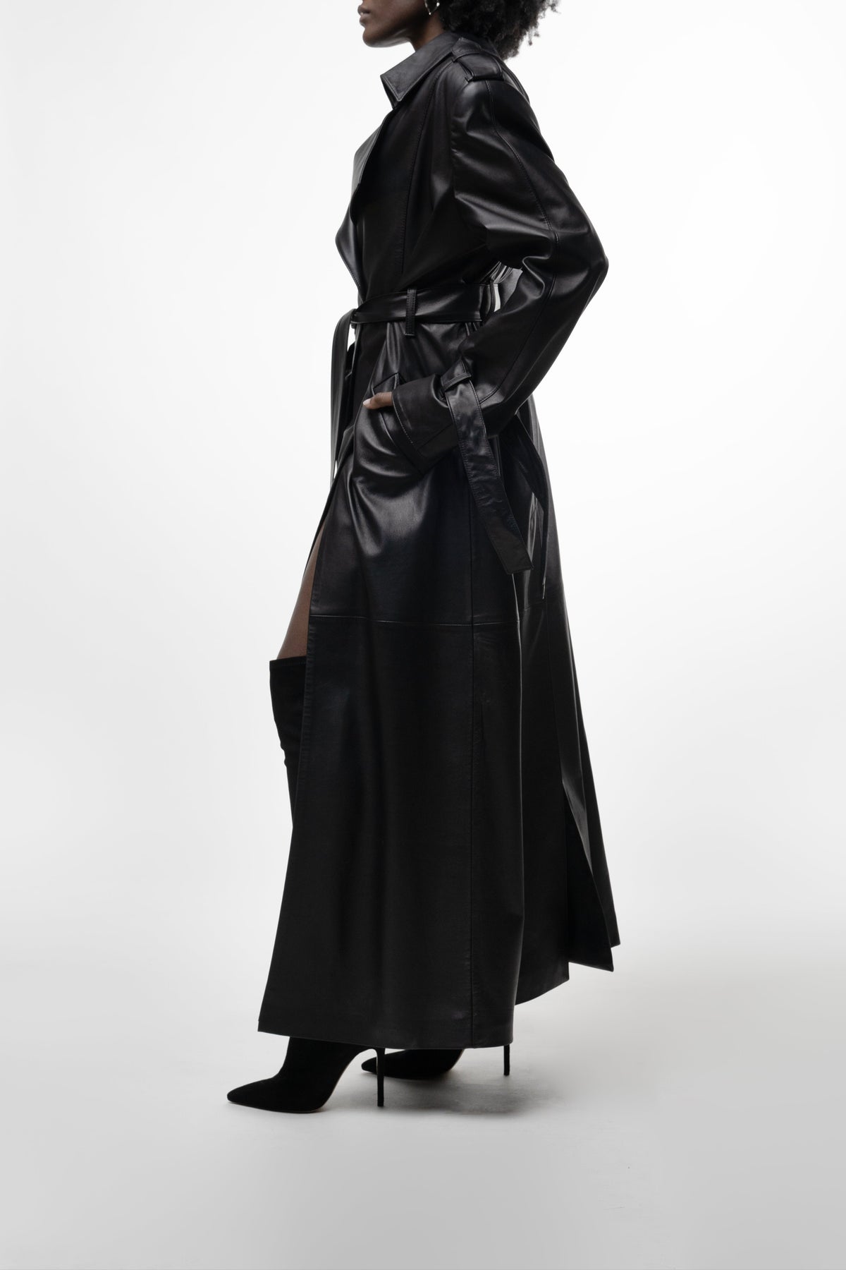 Model in long black leather trench with belt and high side slit