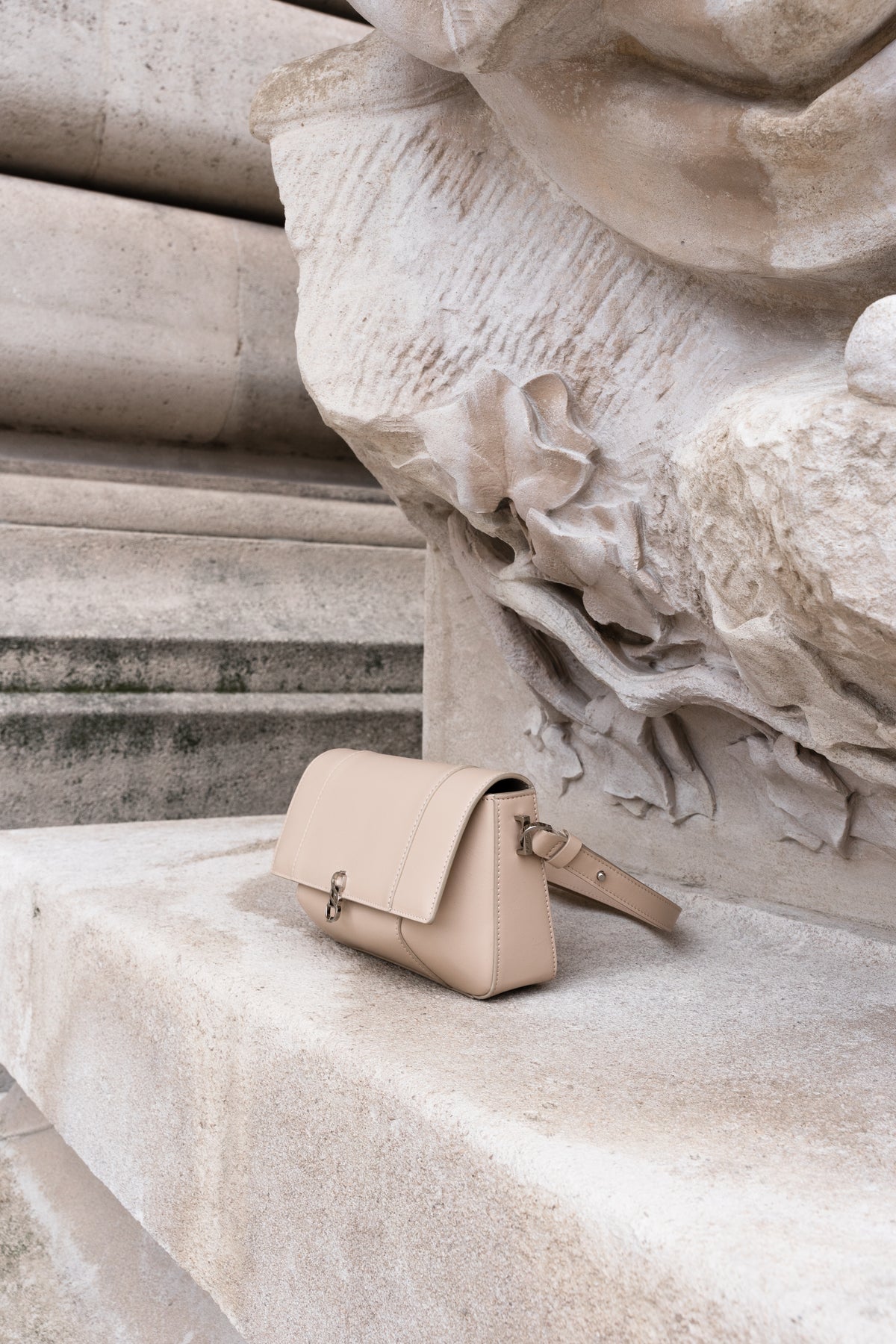 Beige Il Cupola leather bag styled against stone architecture in side profile