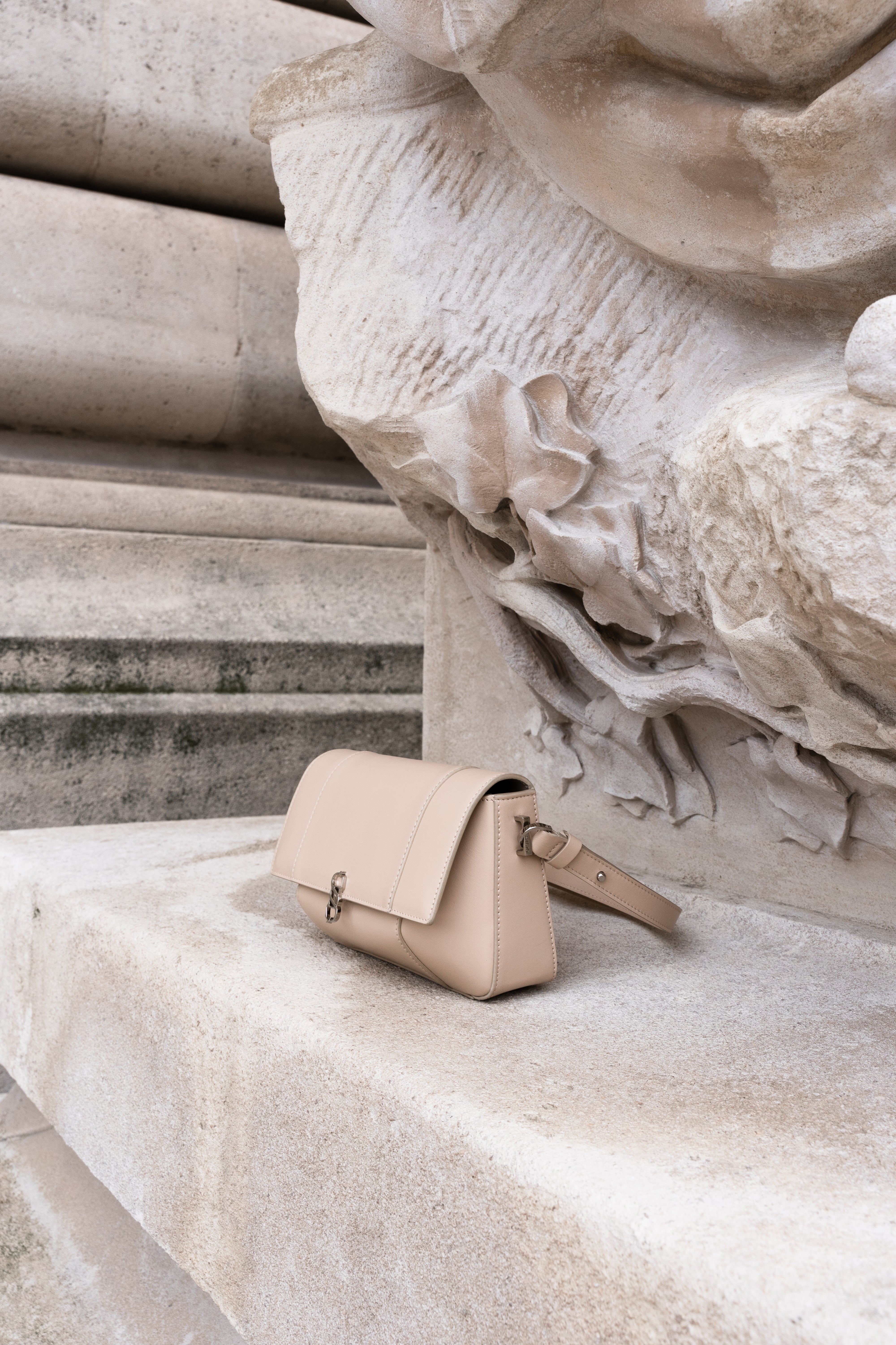 Beige Il Cupola leather bag styled against stone architecture in side profile