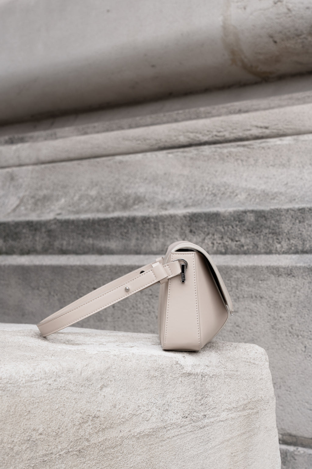 Beige Il Cupola leather bag side view styled on stone surface