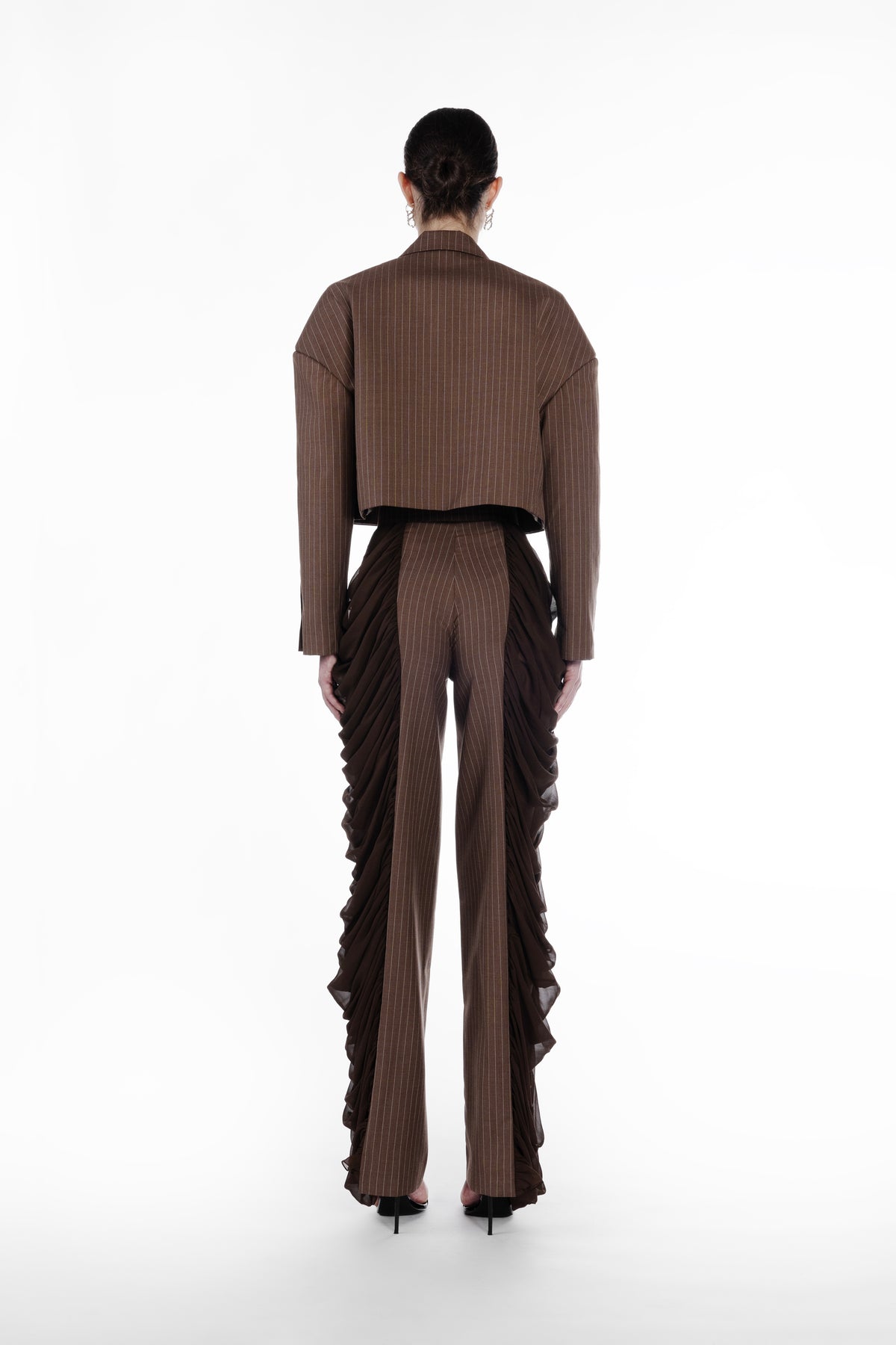 Silk Folds Stripes Trousers in Brown, back view, tailored striped trousers with flowing silk folds along the sides and a clean elongated silhouette. Falling Shoulders Stripes Jacket by SAGIO in brown beige pinstripe wool, back view, structured cropped jacket with sheer gathered side panels