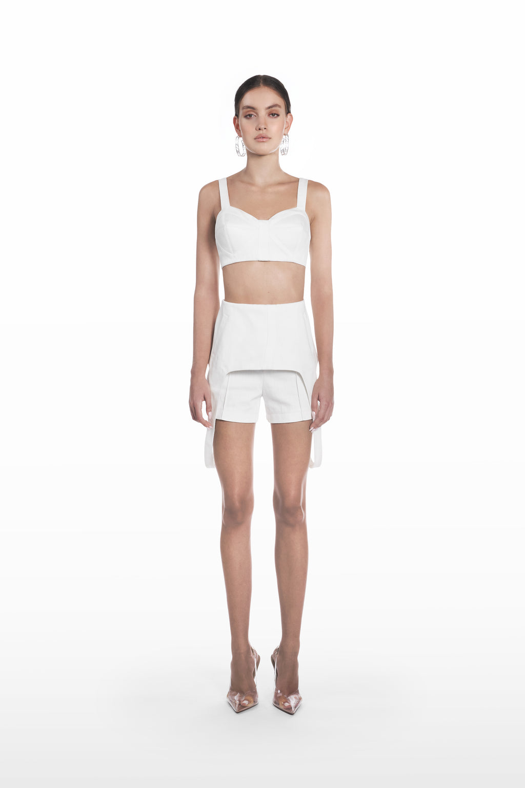 Denim falling shorts in white, front view with sculptural overlay and tailored silhouette styled with a matching cropped top