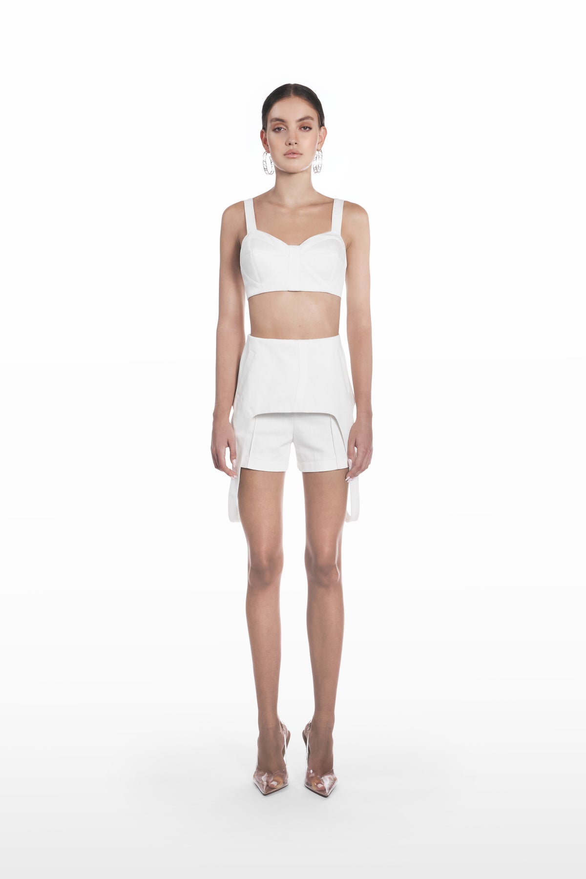 Denim falling shorts in white, front view with sculptural overlay and tailored silhouette styled with a matching cropped top