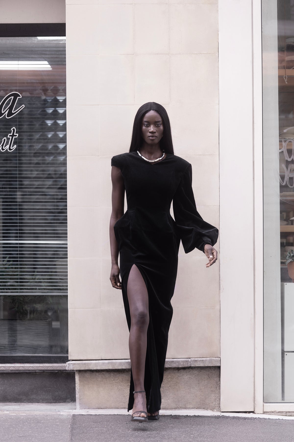 Black asymmetrical long dress with puff sleeve and high slit, front view