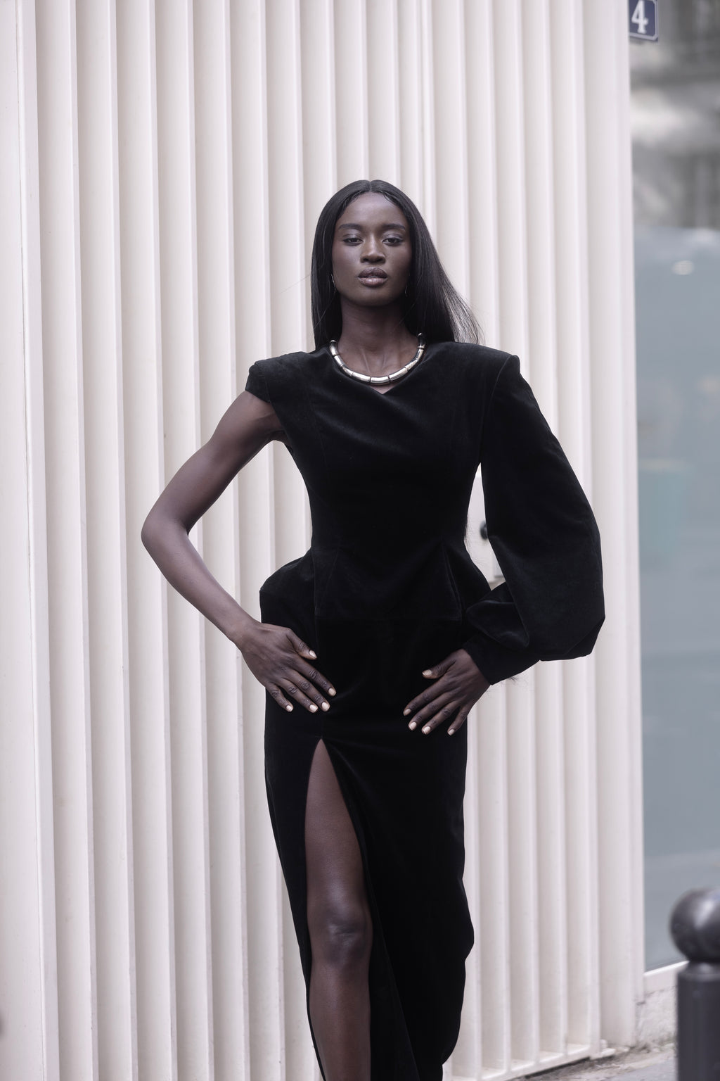 Black one-sleeve evening dress, walking shot, thigh-high slit visible