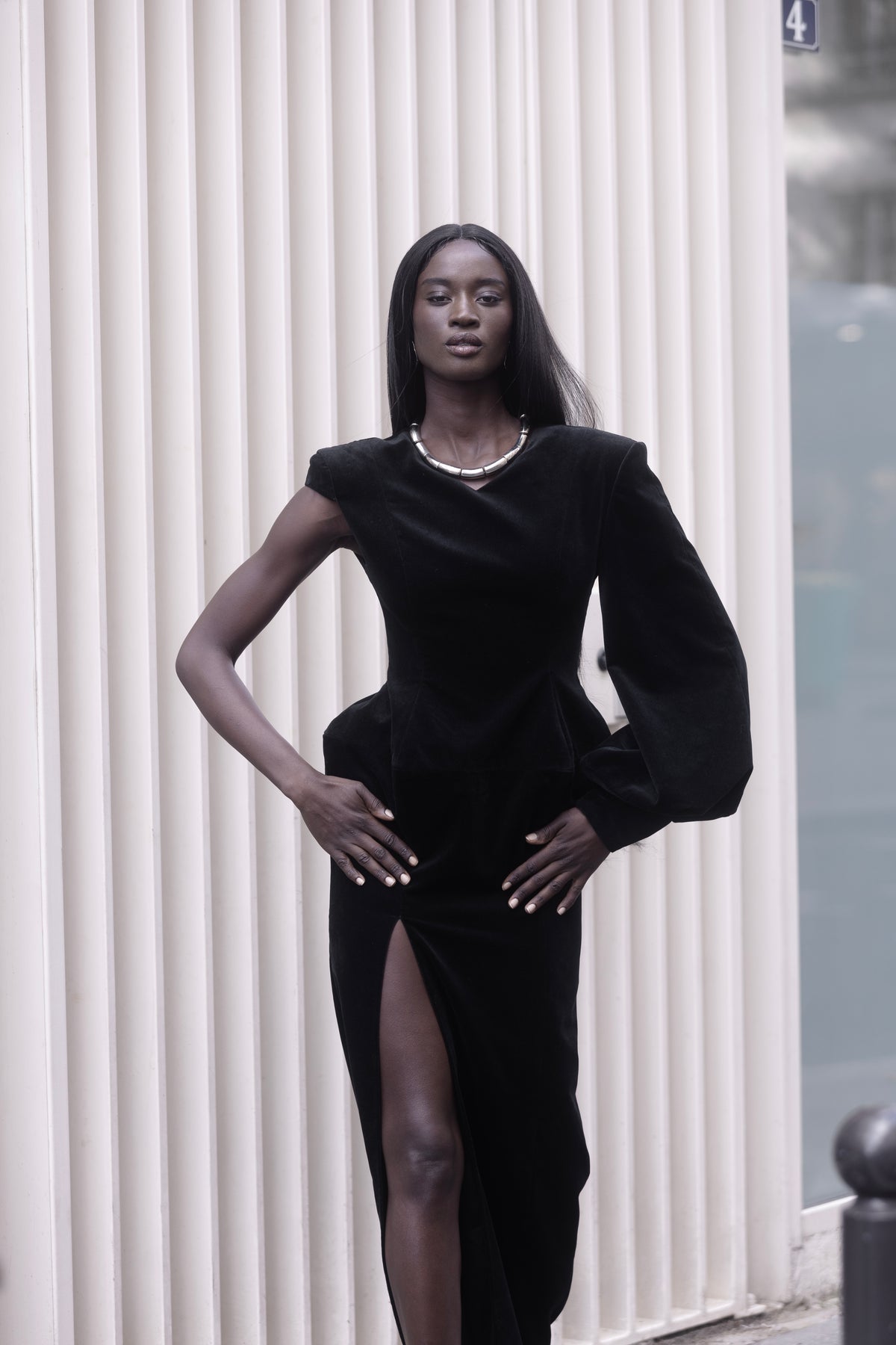 Black one-sleeve evening dress, walking shot, thigh-high slit visible