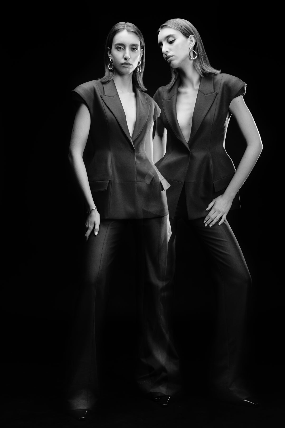 Women’s black hip-length blazer with sharp lapels and cap sleeves, double exposure on black