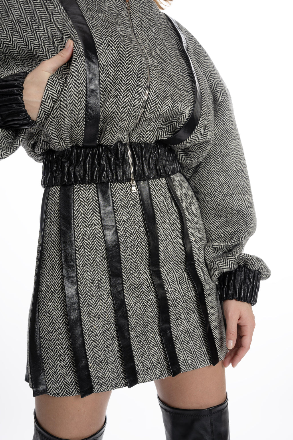 Close-up of herringbone tweed fabric and leather placket stripes on mini skirt