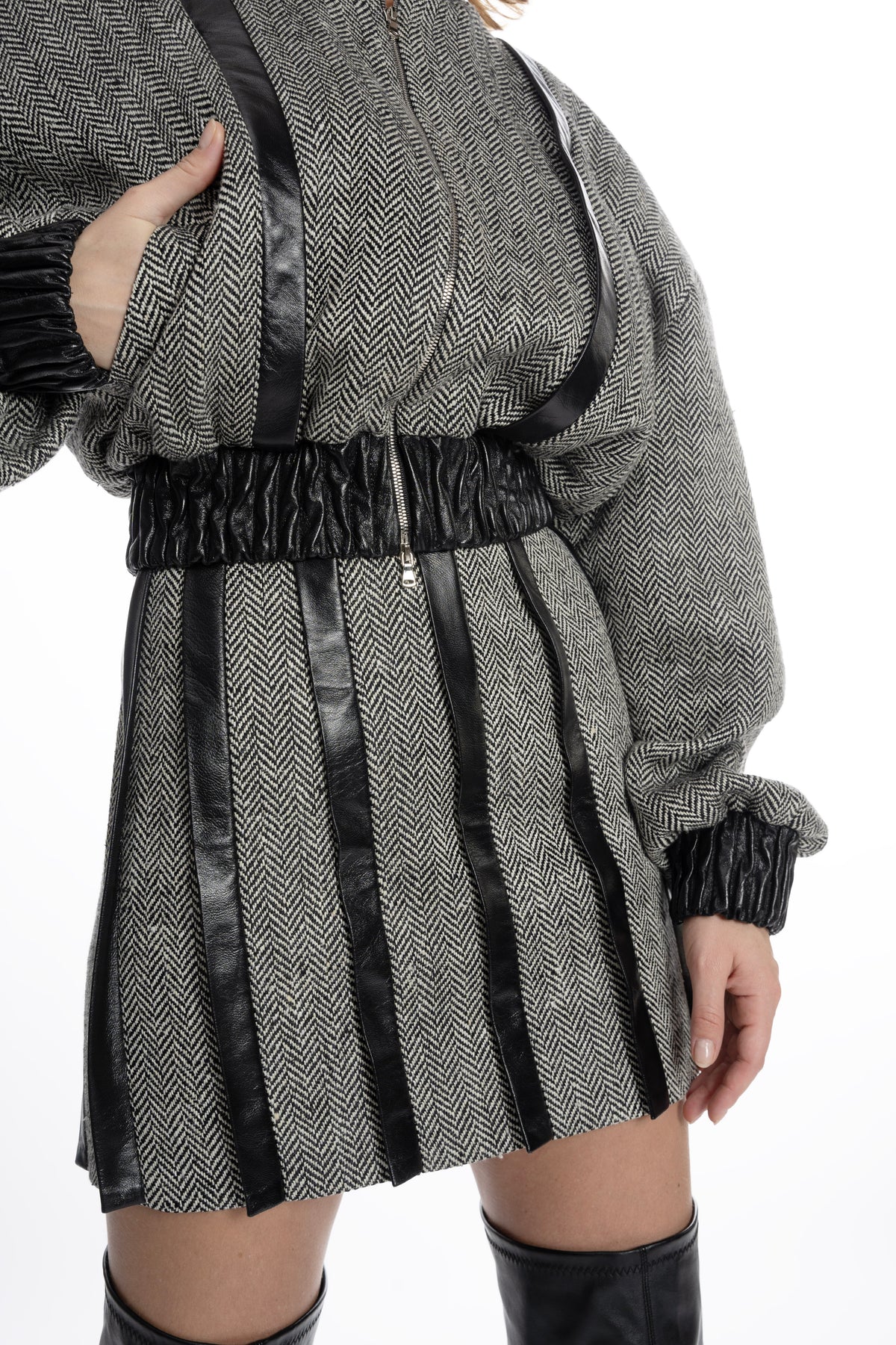Close-up of herringbone tweed fabric and leather placket stripes on mini skirt