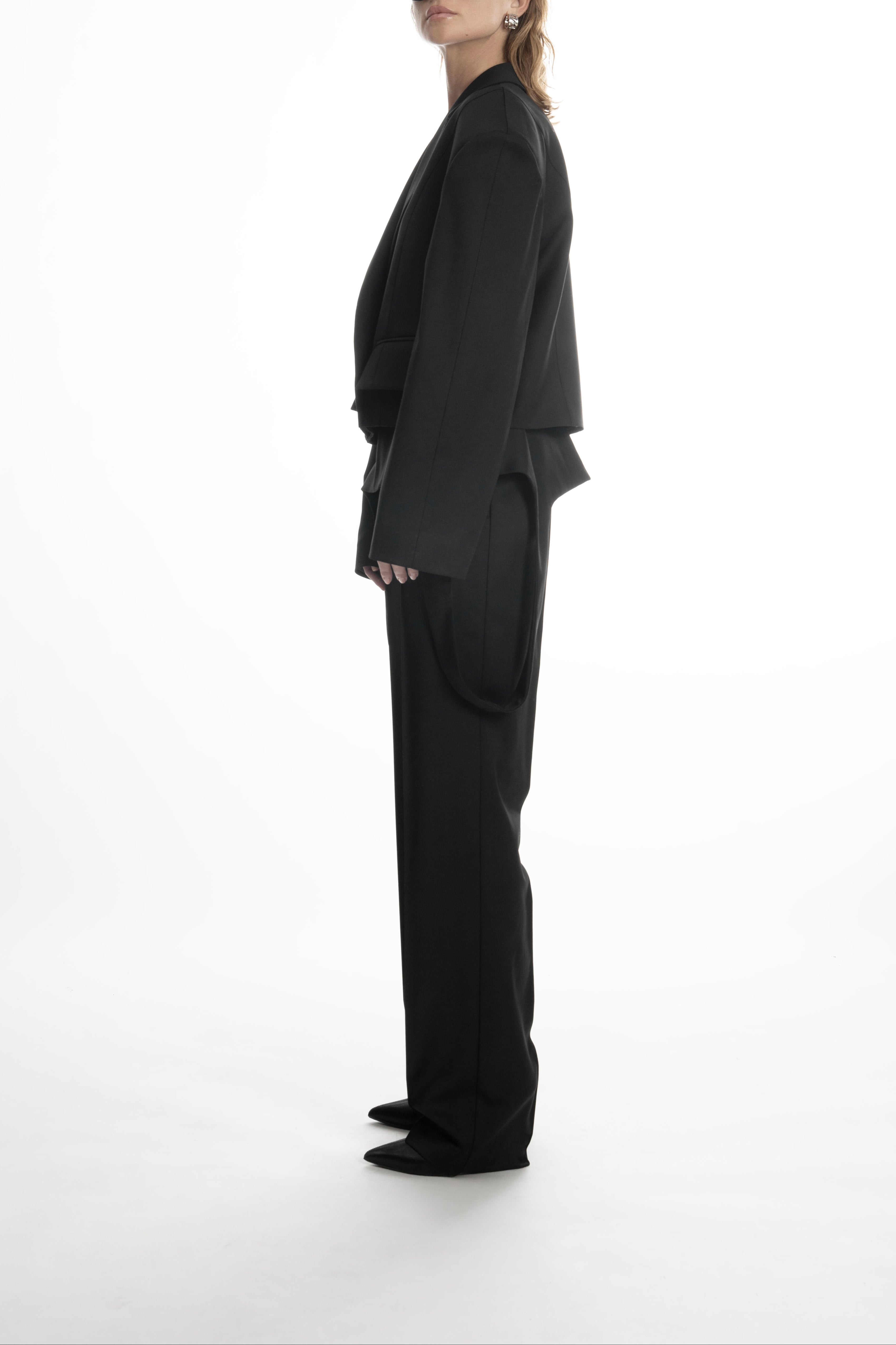 Model in black cropped wool blazer, showing the fluid, dropped-shoulder line and boxy fit.