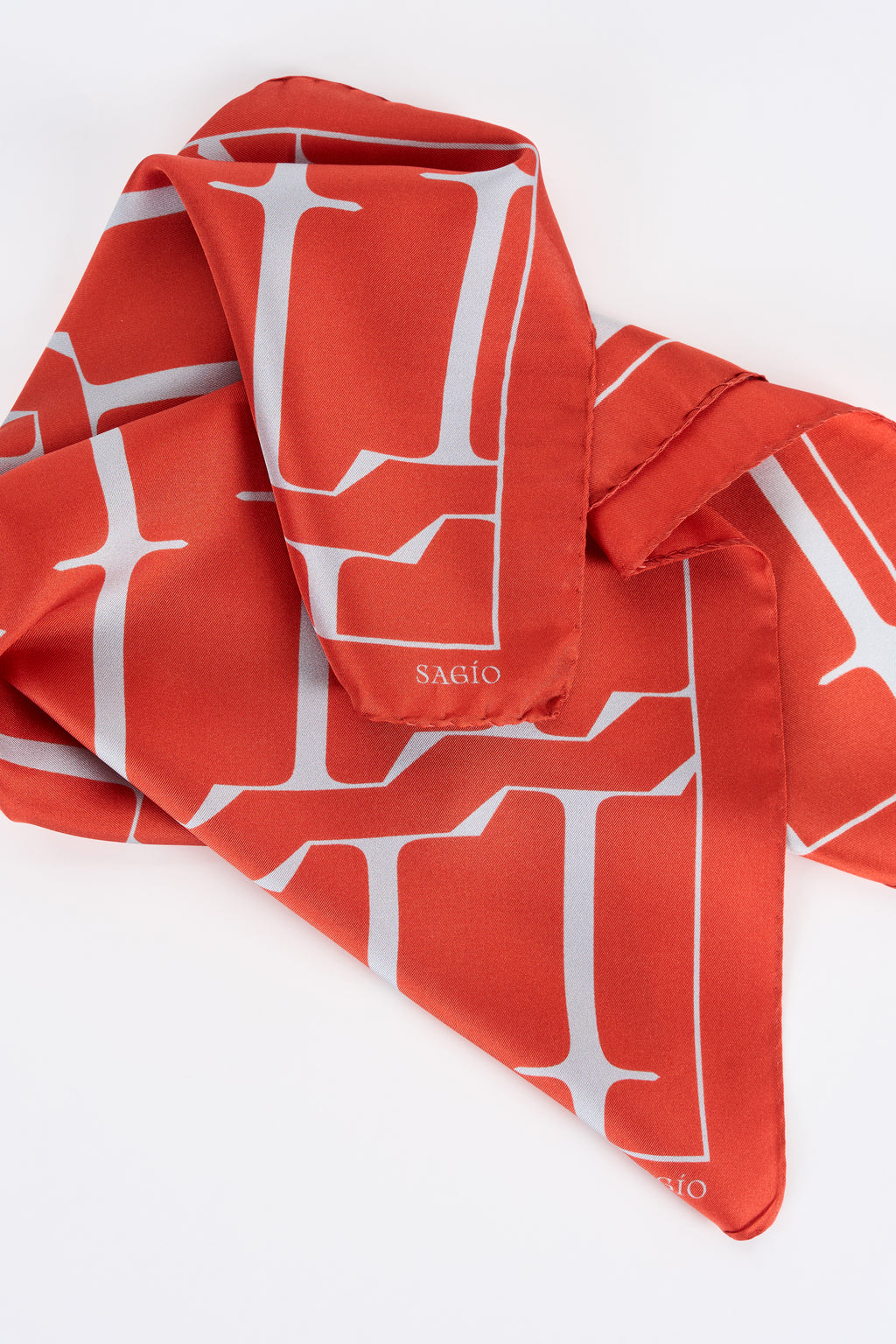 Vermilion red designer silk carré scarf with white graphic monogram in draped detail view