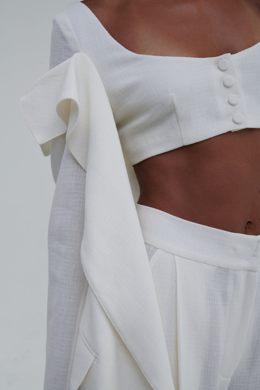 White linen-cotton fabric close-up, waistband and draped lapel detail