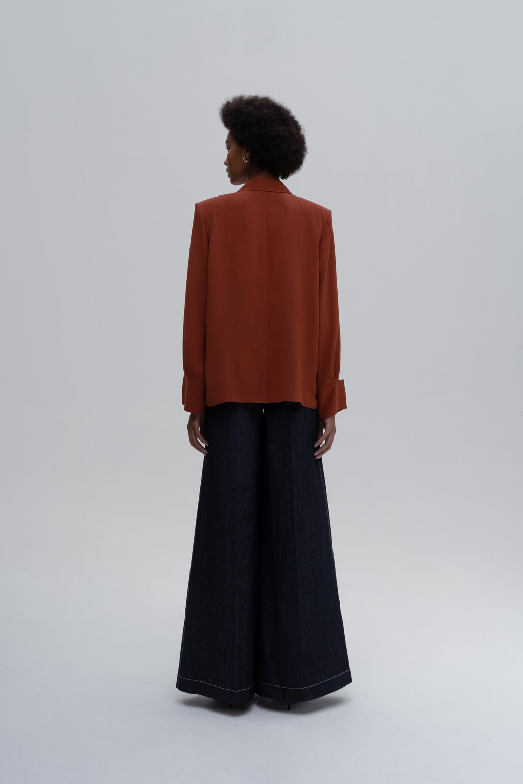Model wearing the Silk Shirt by Sagio featuring a relaxed-fit, long-sleeve red silk blouse with a classic collar and concealed button placket.