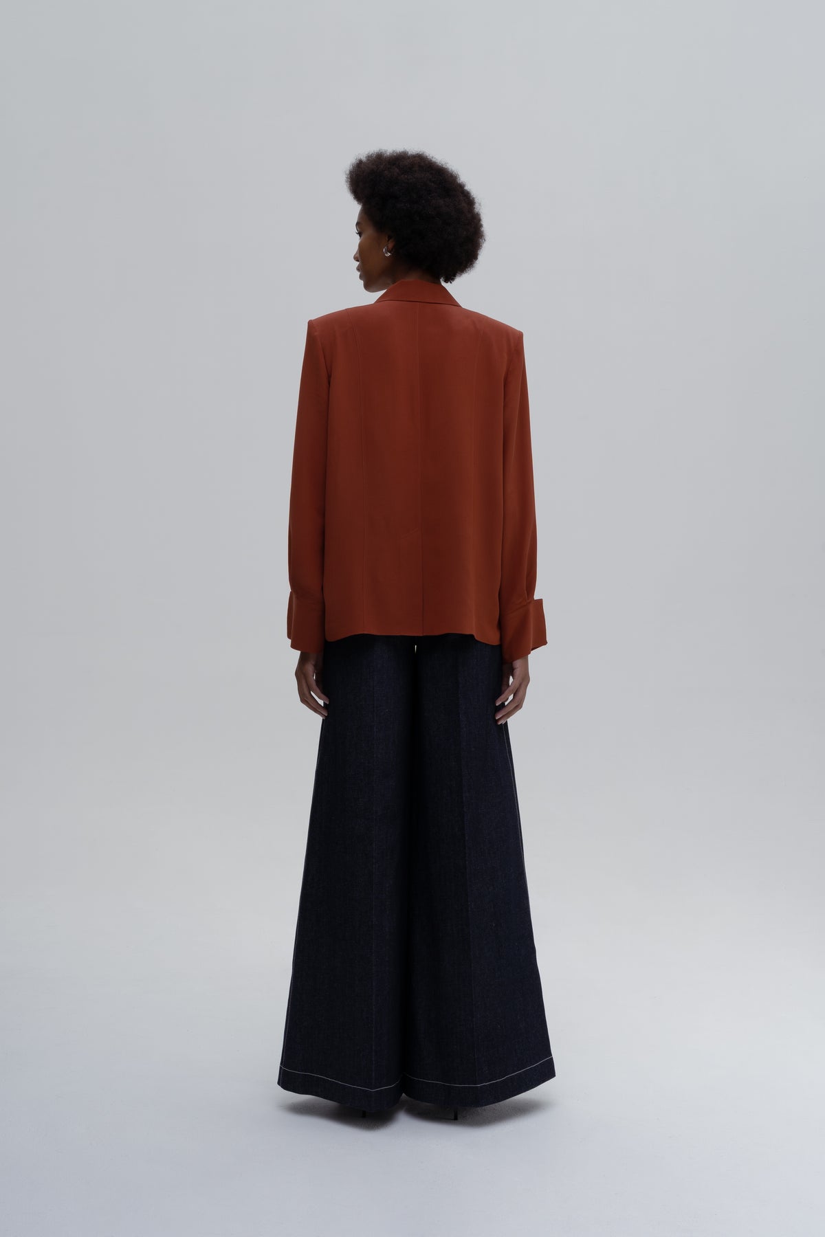 Model wearing the Silk Shirt by Sagio featuring a relaxed-fit, long-sleeve red silk blouse with a classic collar and concealed button placket.