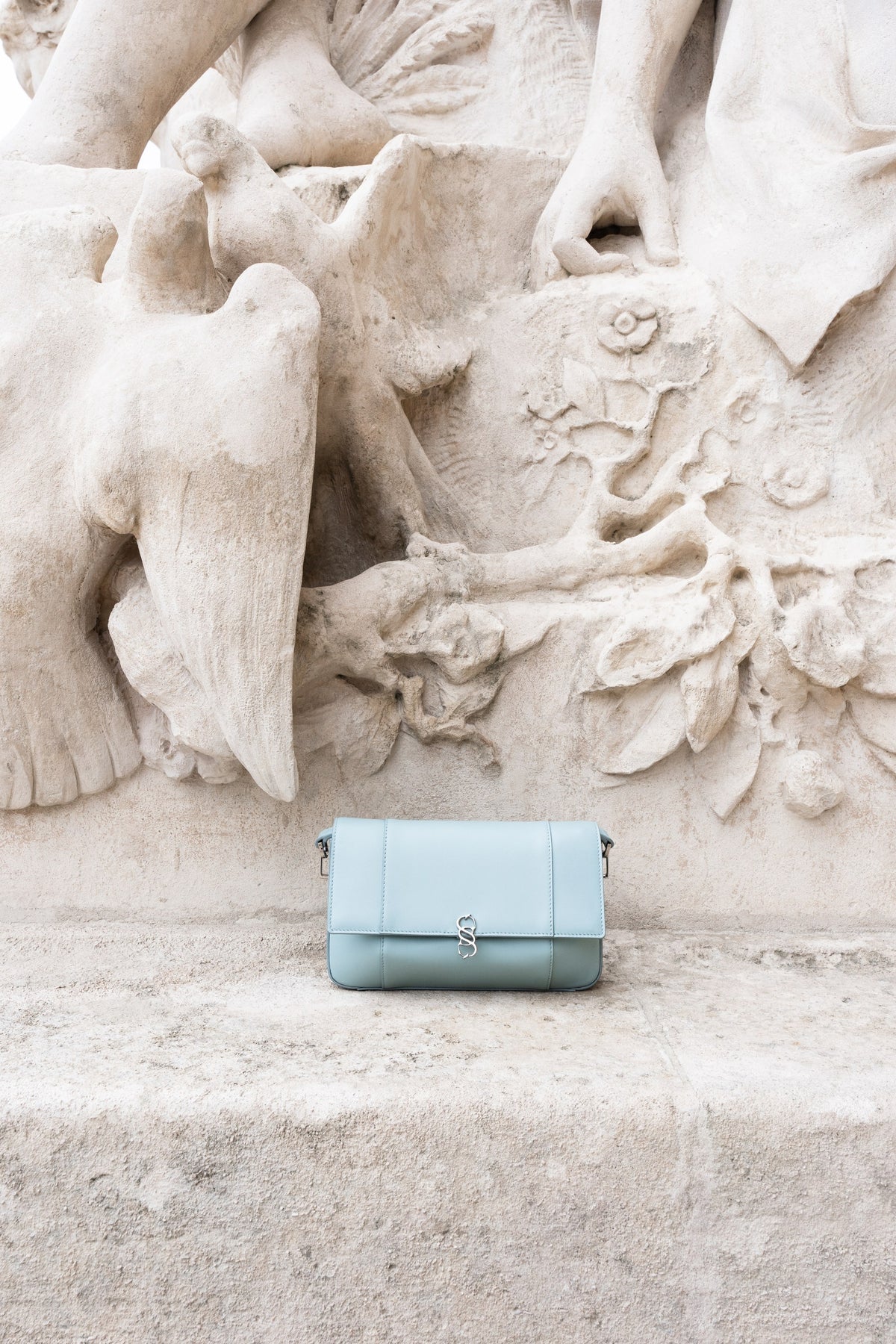 Pale blue leather bag on a carved stone ledge