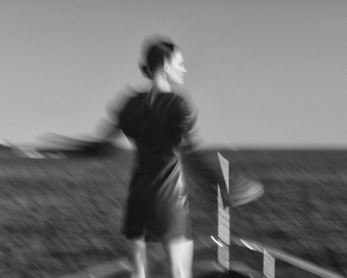Model in motion in a black dress by the sea