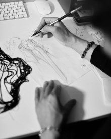 Hand sketching a dress at the atelier desk